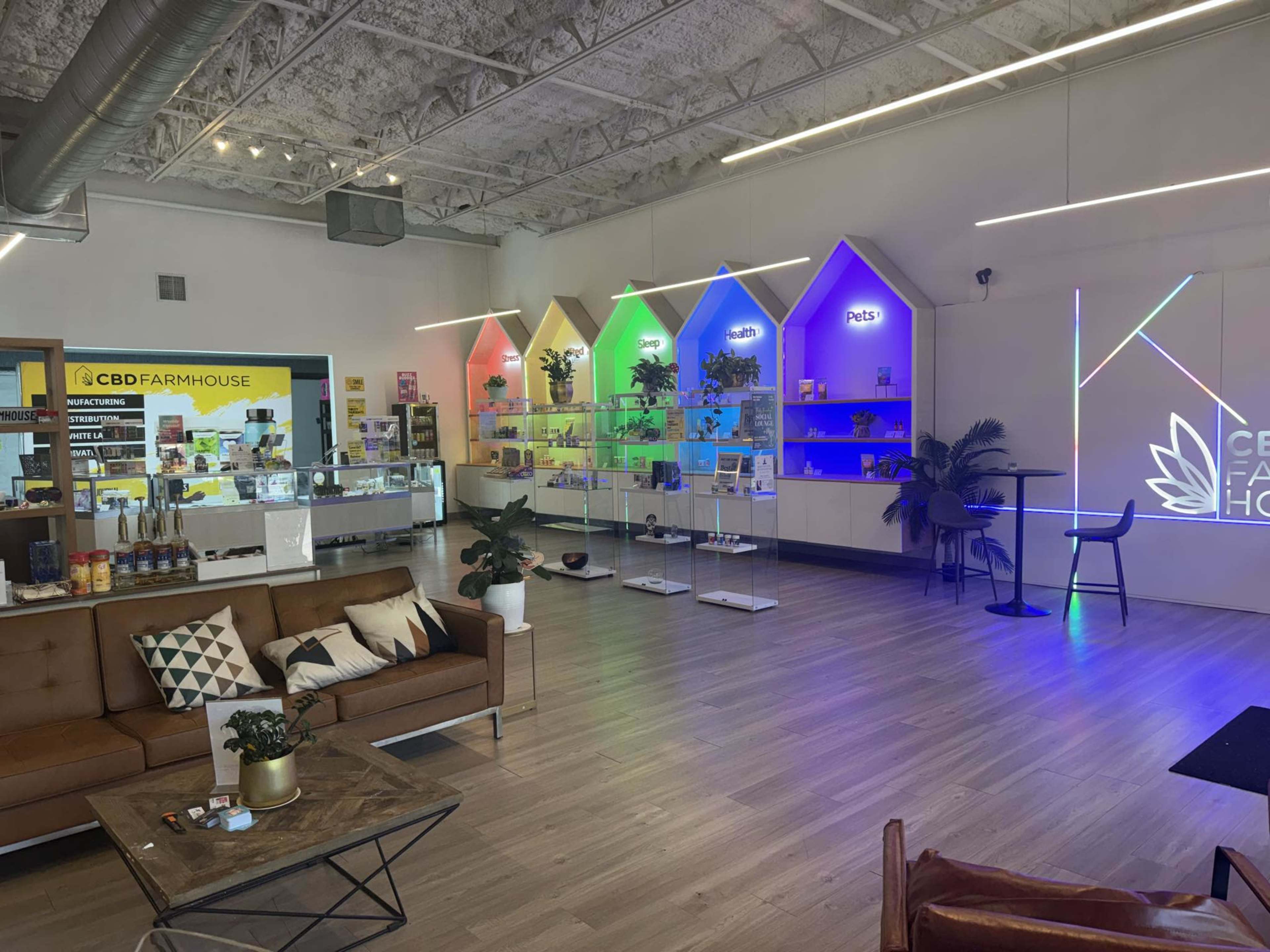 A modern retail space with colorful lighting, displaying products on shelves, and a seating area with a couch and coffee table.