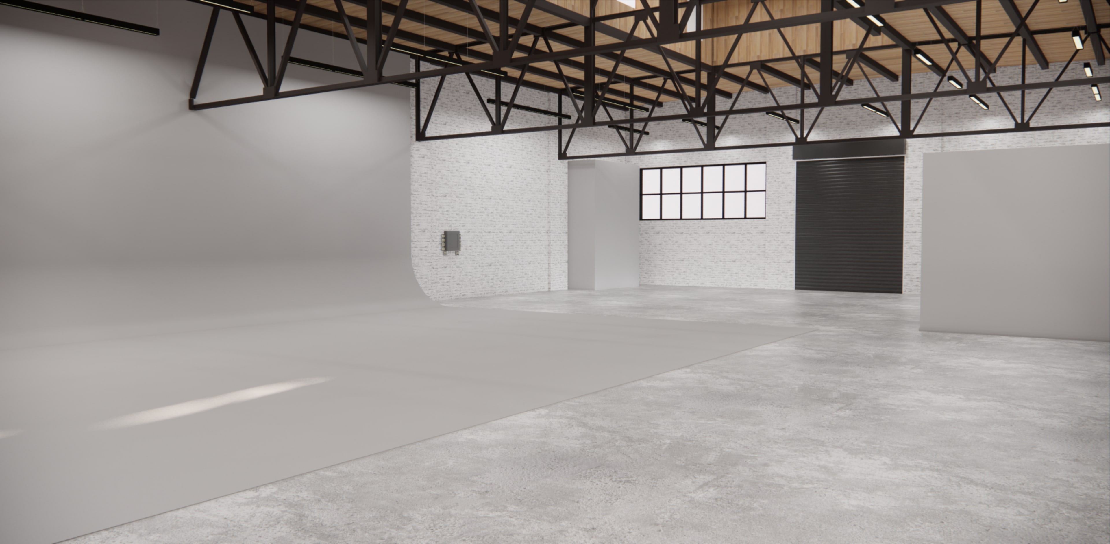 A spacious studio with high ceilings, industrial beams, and gray flooring, featuring a seamless backdrop and large windows.