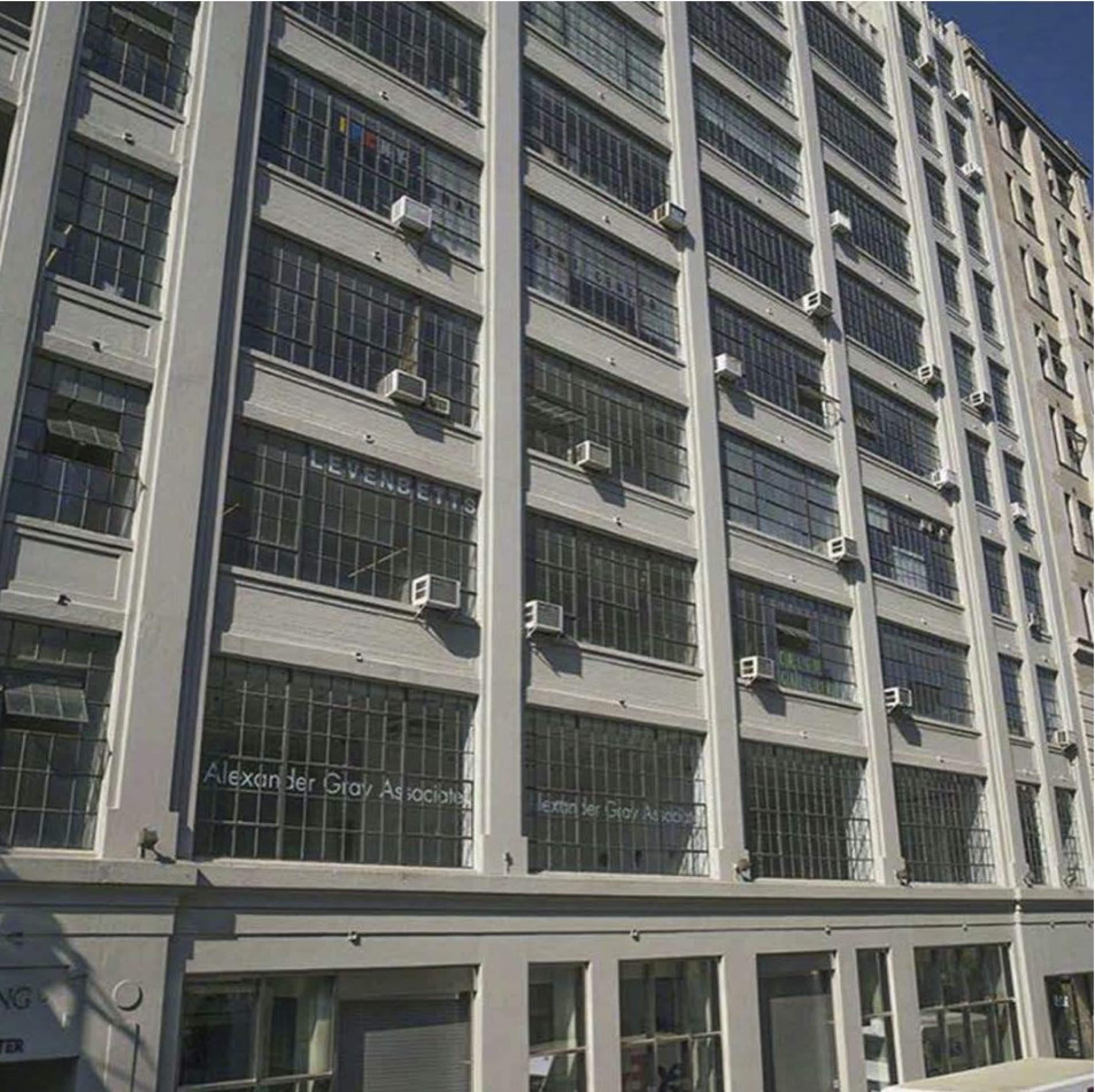 The image shows a multi-story building facade with large windows and several air conditioning units installed.