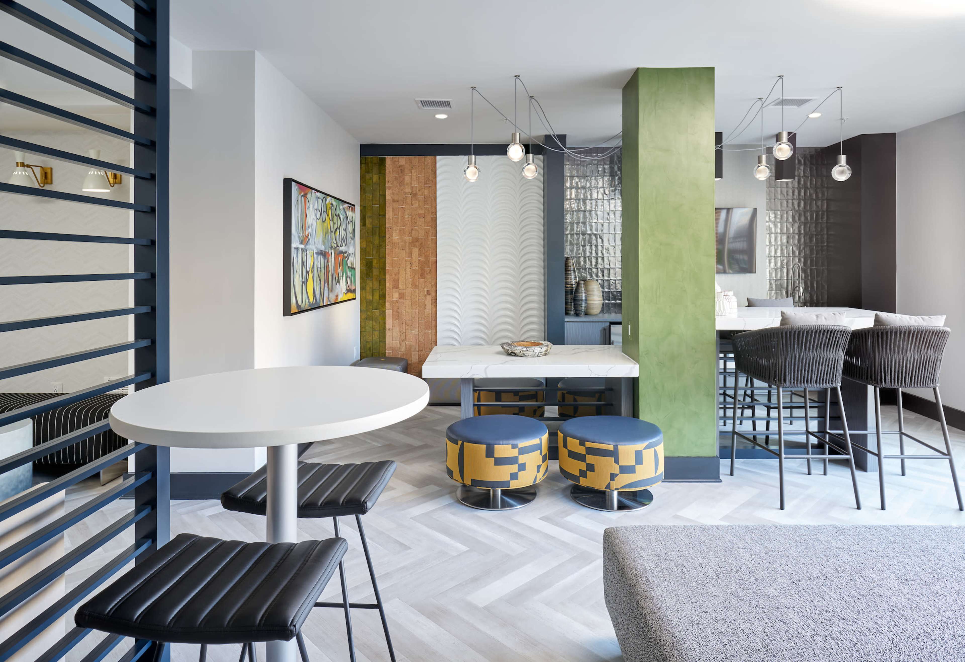 A modern interior space featuring a dining area with a table, barstools, and distinct seating options, alongside a decorative wall and artistic elements.