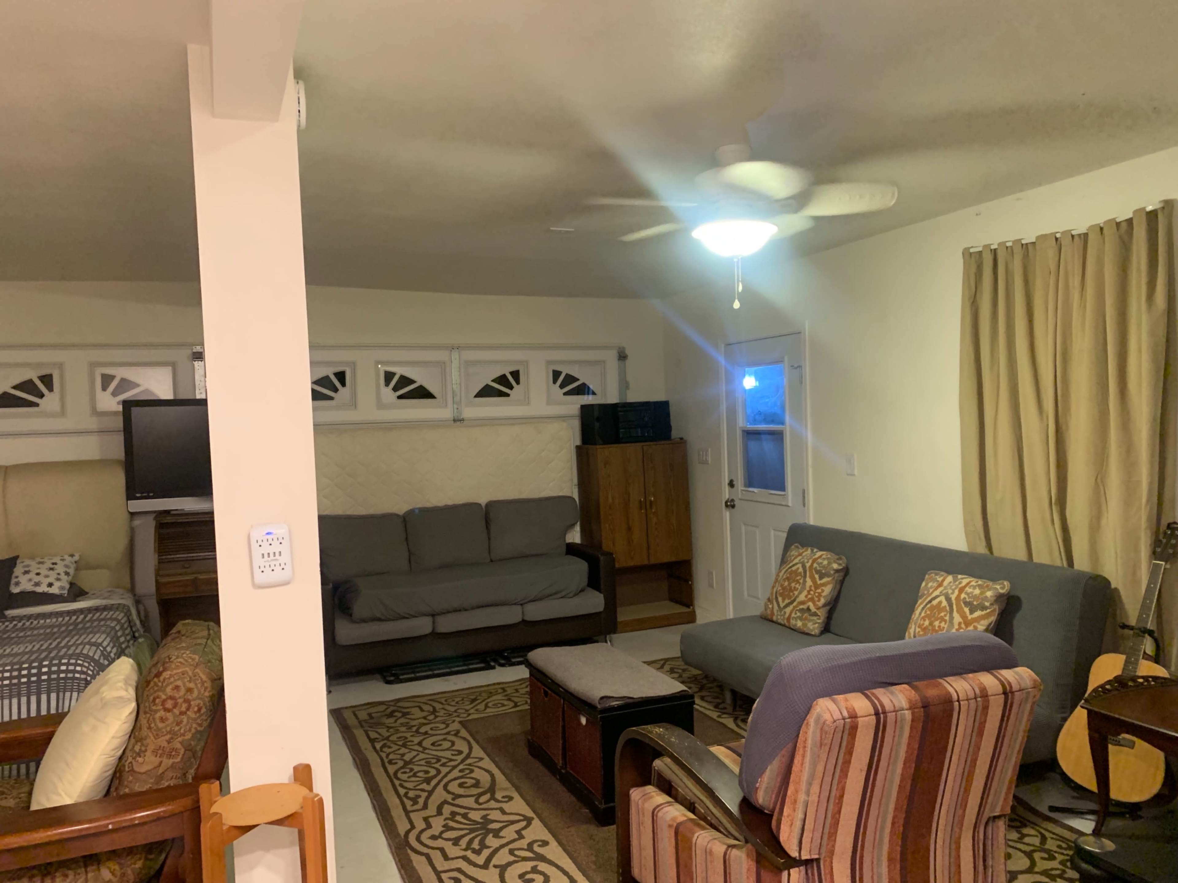 A living room with various seating options, a television, and a door leading outside.