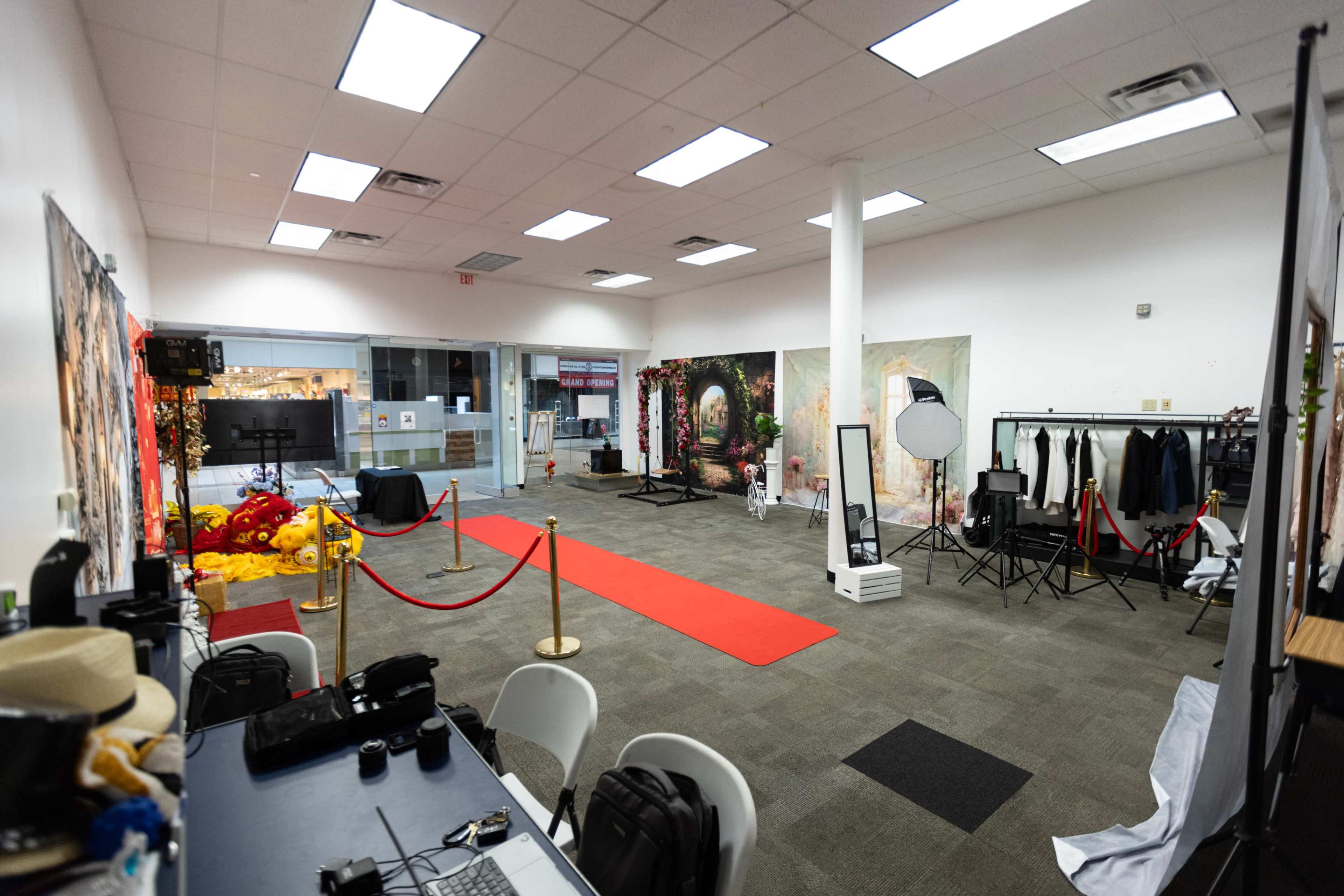 The image shows a spacious event area with a red carpet, a photo backdrop, and various equipment set up for a photoshoot or event.