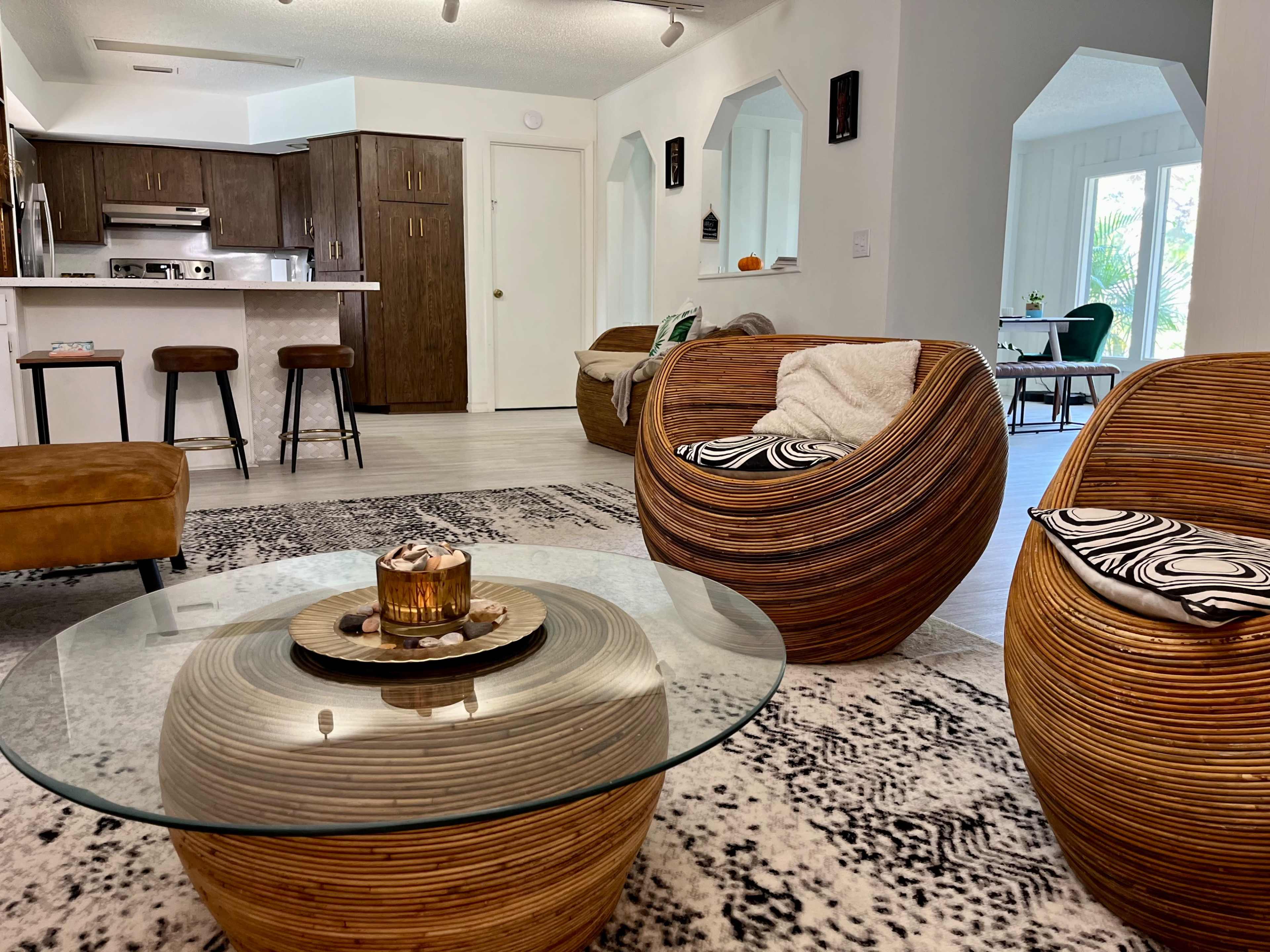 A modern living room furnished with curved wooden chairs, a round glass coffee table, and a cozy seating area.
