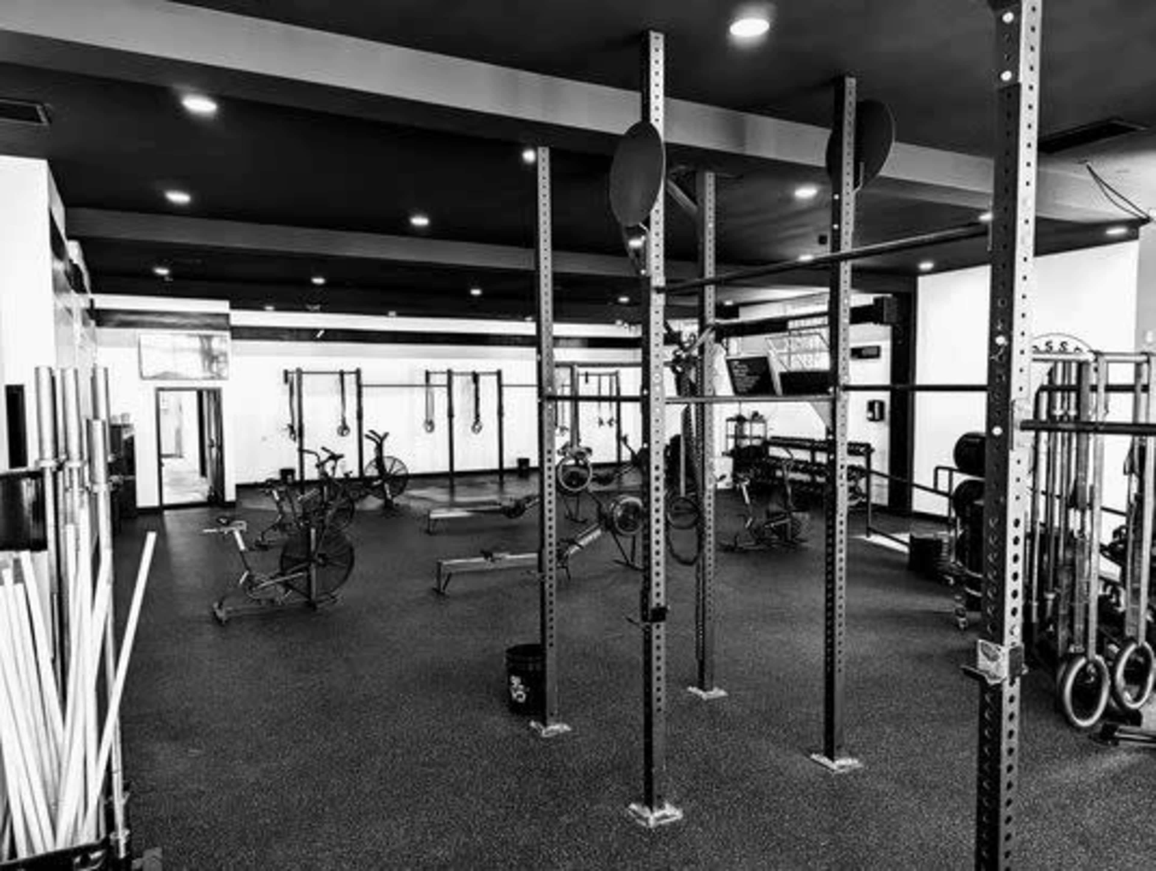 A spacious gym interior with various exercise equipment, including weight racks and stationary bikes, arranged in an organized manner on a rubberized floor.