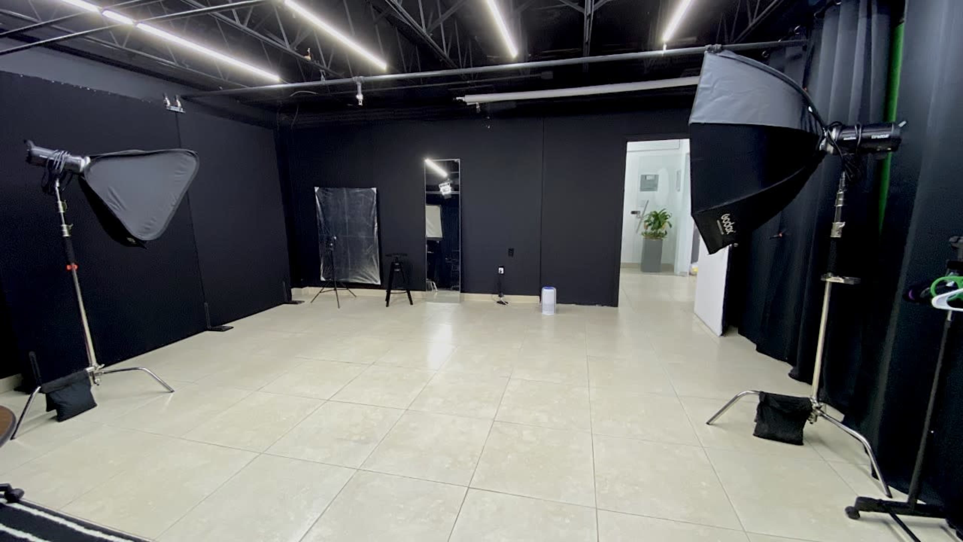 A photography studio with two light setups, a mirror, and a door leading to another room.