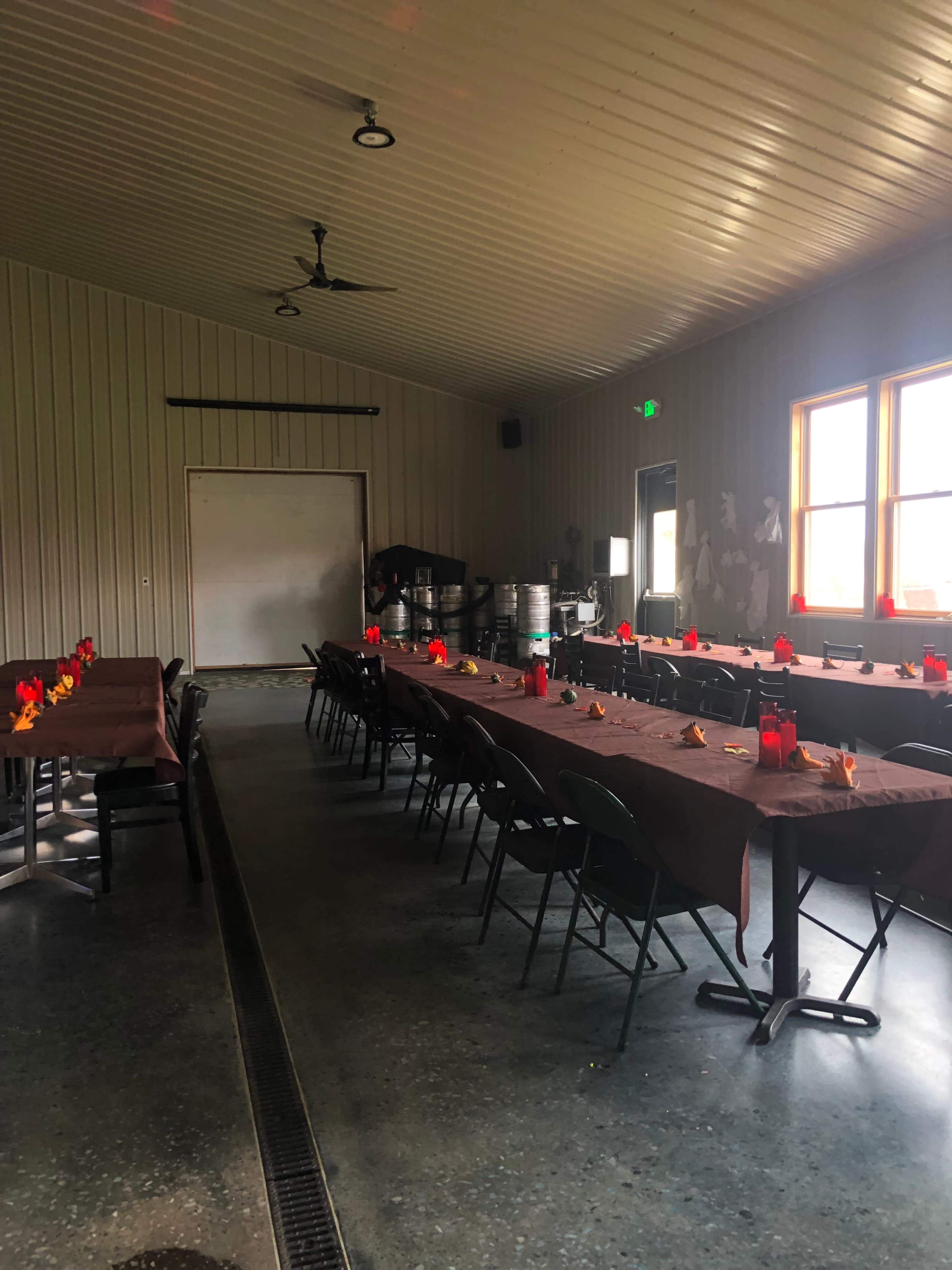 The image shows a spacious dining area with multiple long tables arranged side by side, adorned with brown tablecloths and red napkin decorations.