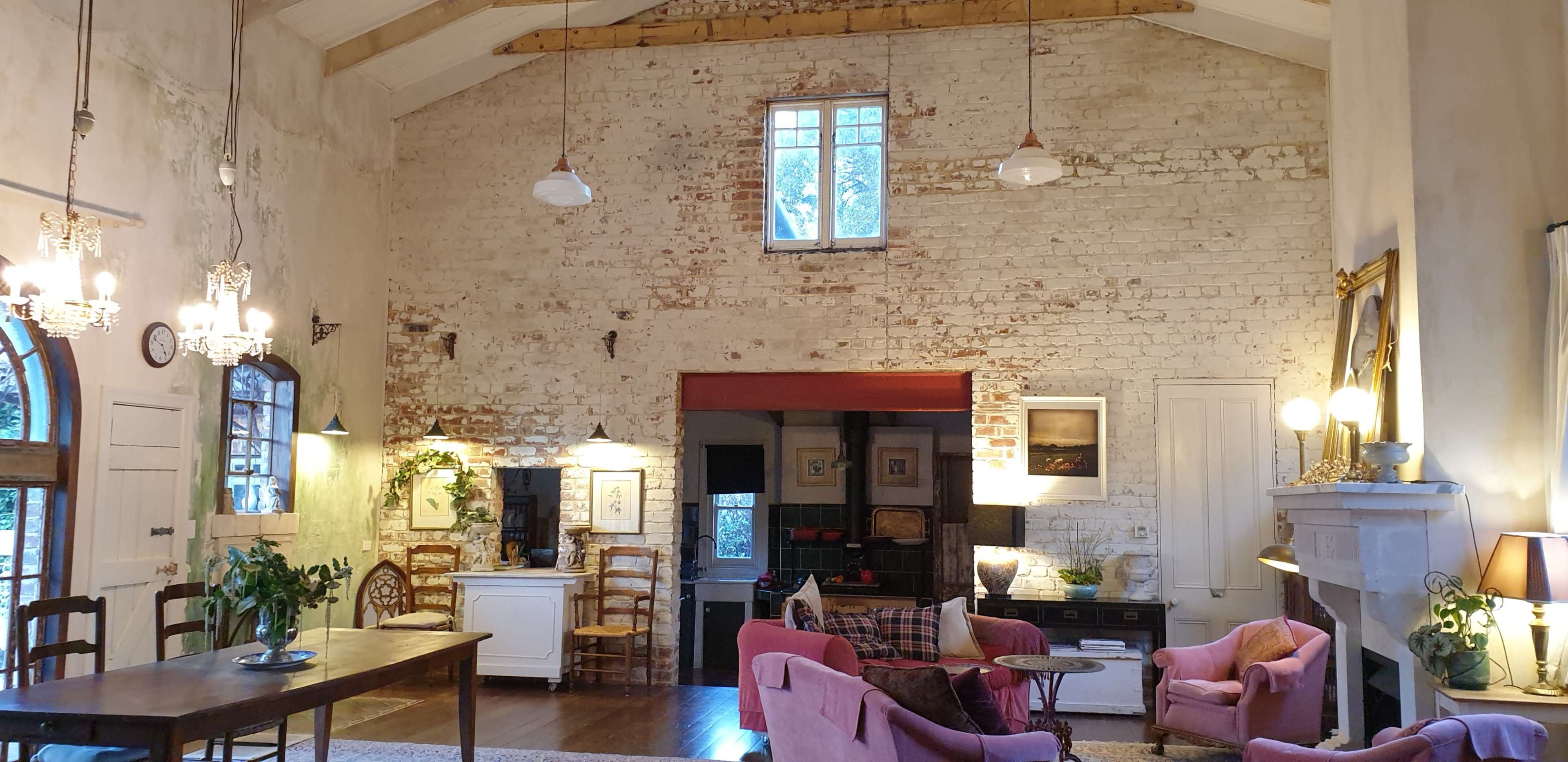 The interior of a spacious living area features exposed brick walls, wooden beams, and a mix of rustic and modern furnishings.