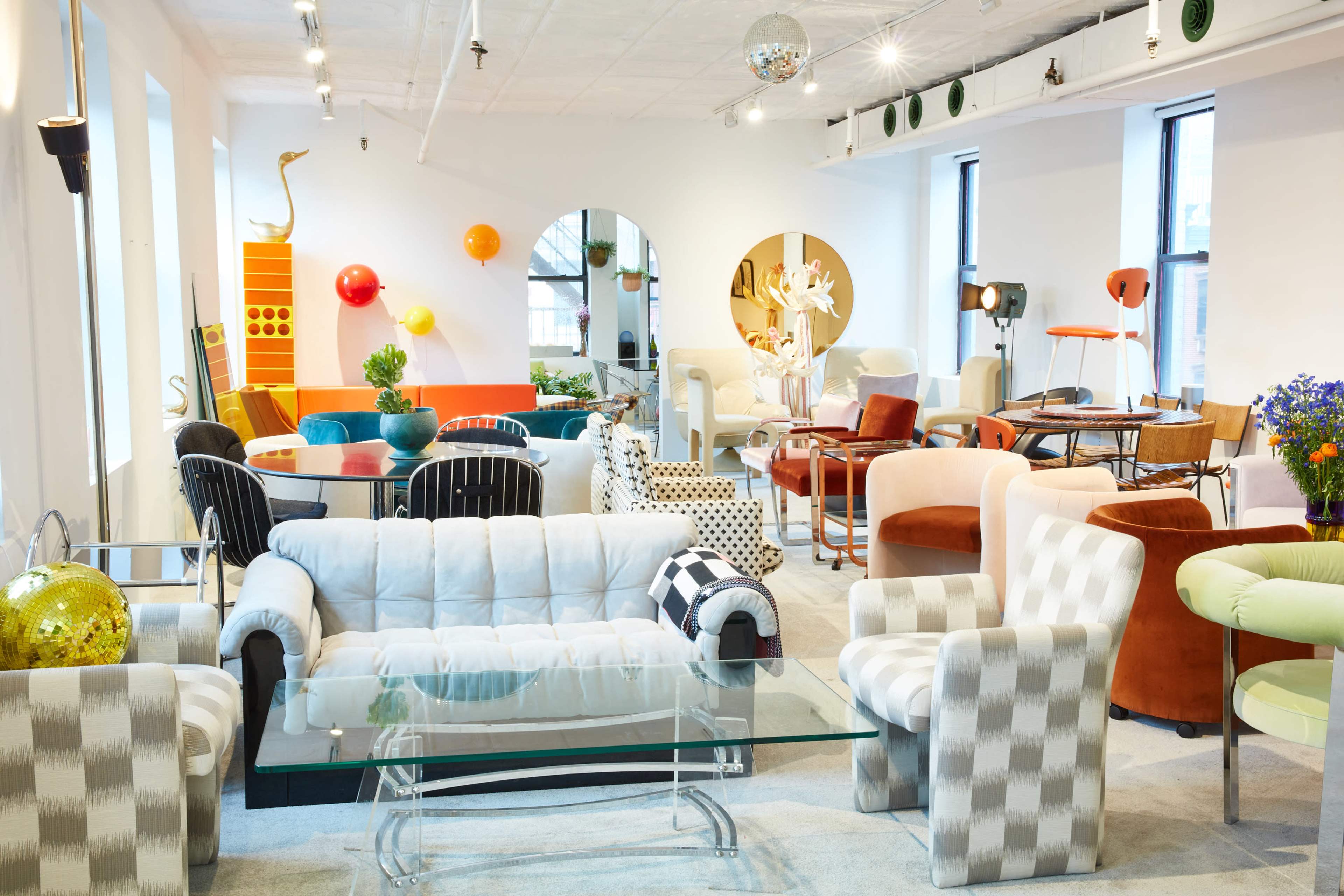 The image shows a vibrant furniture showroom filled with various colorful chairs, sofas, and decorative items arranged thoughtfully in an open space.