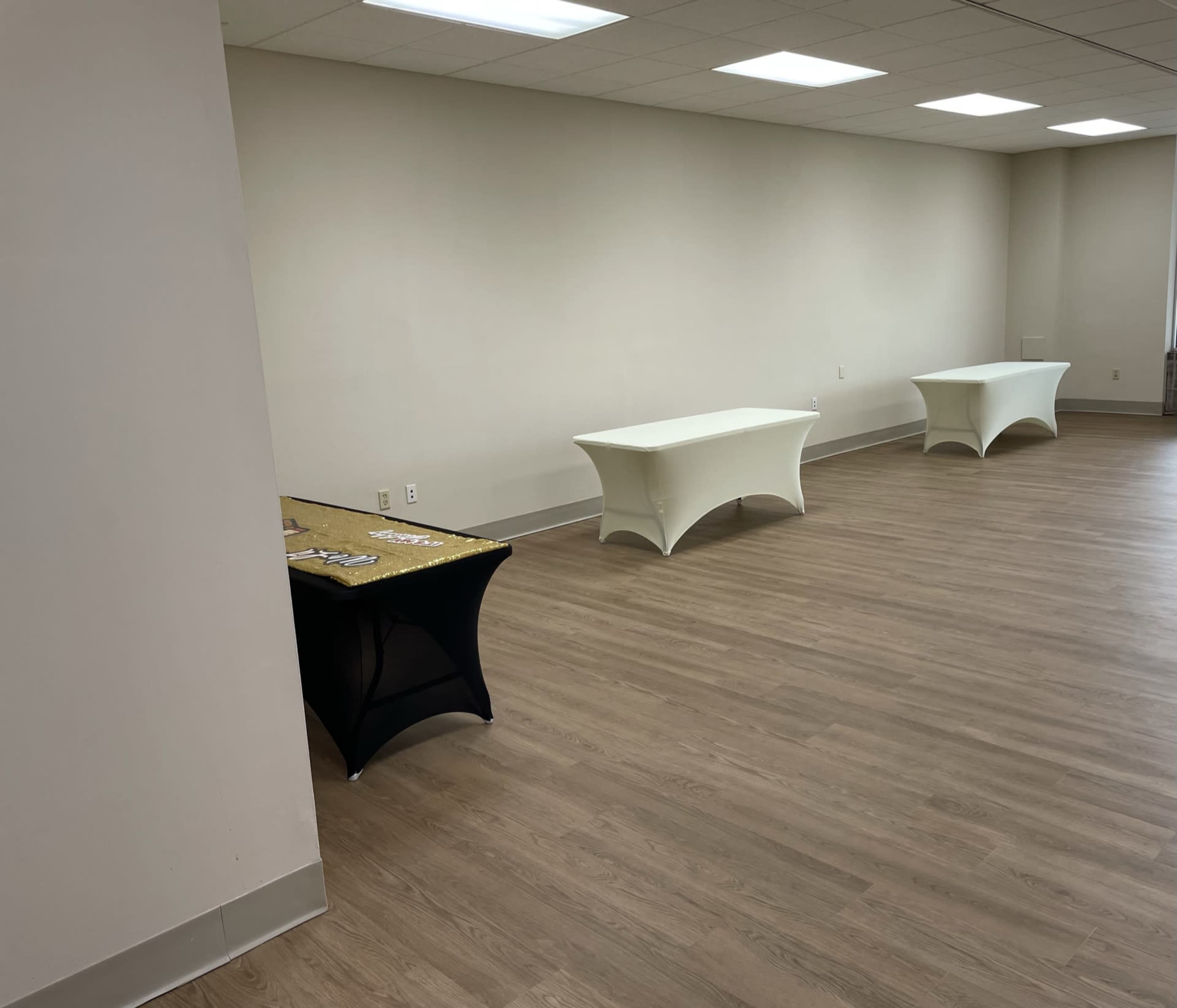 A sparsely furnished room with three table setups against a plain wall.