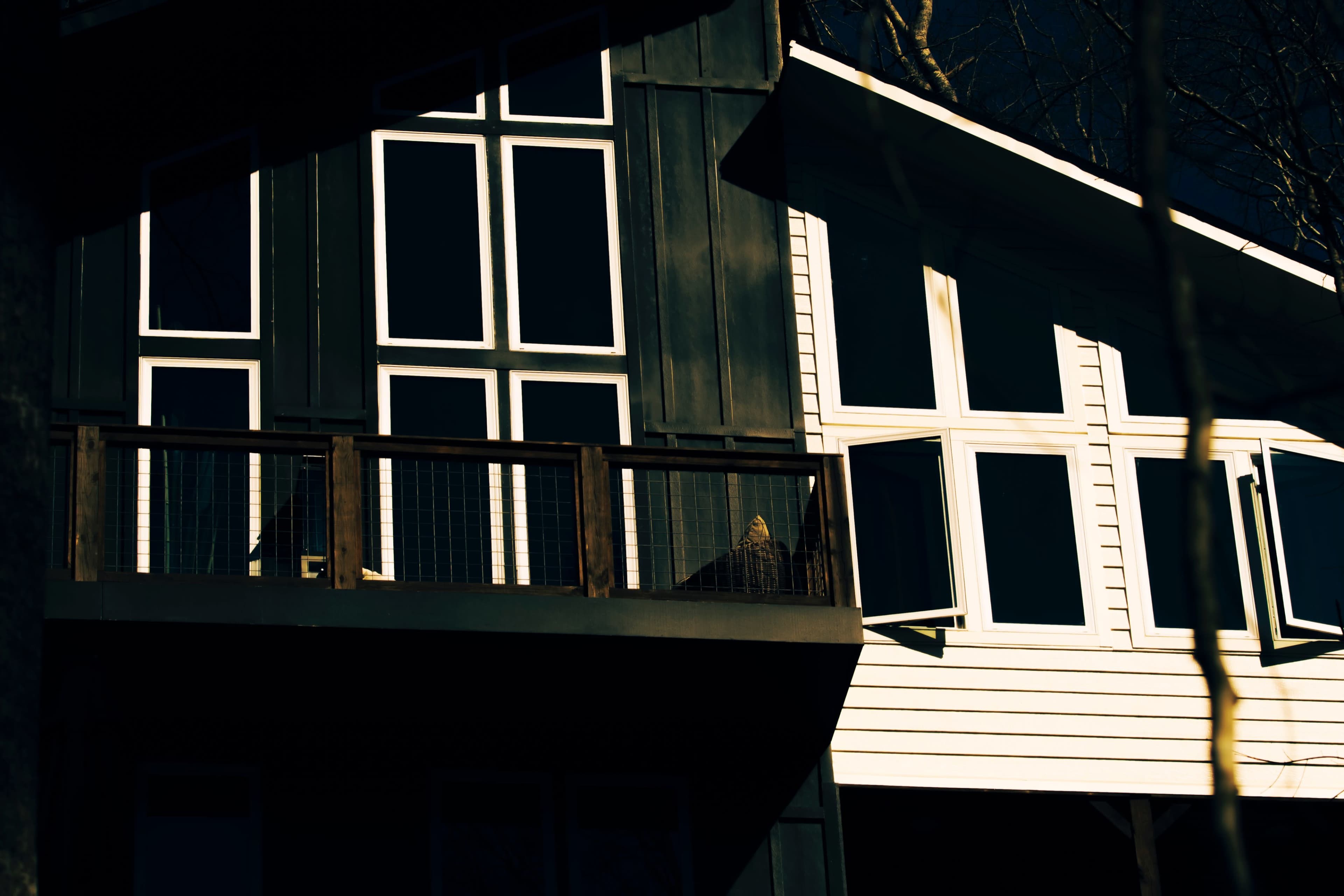 The image depicts two modern houses with large windows, one black and the other white, situated next to each other.