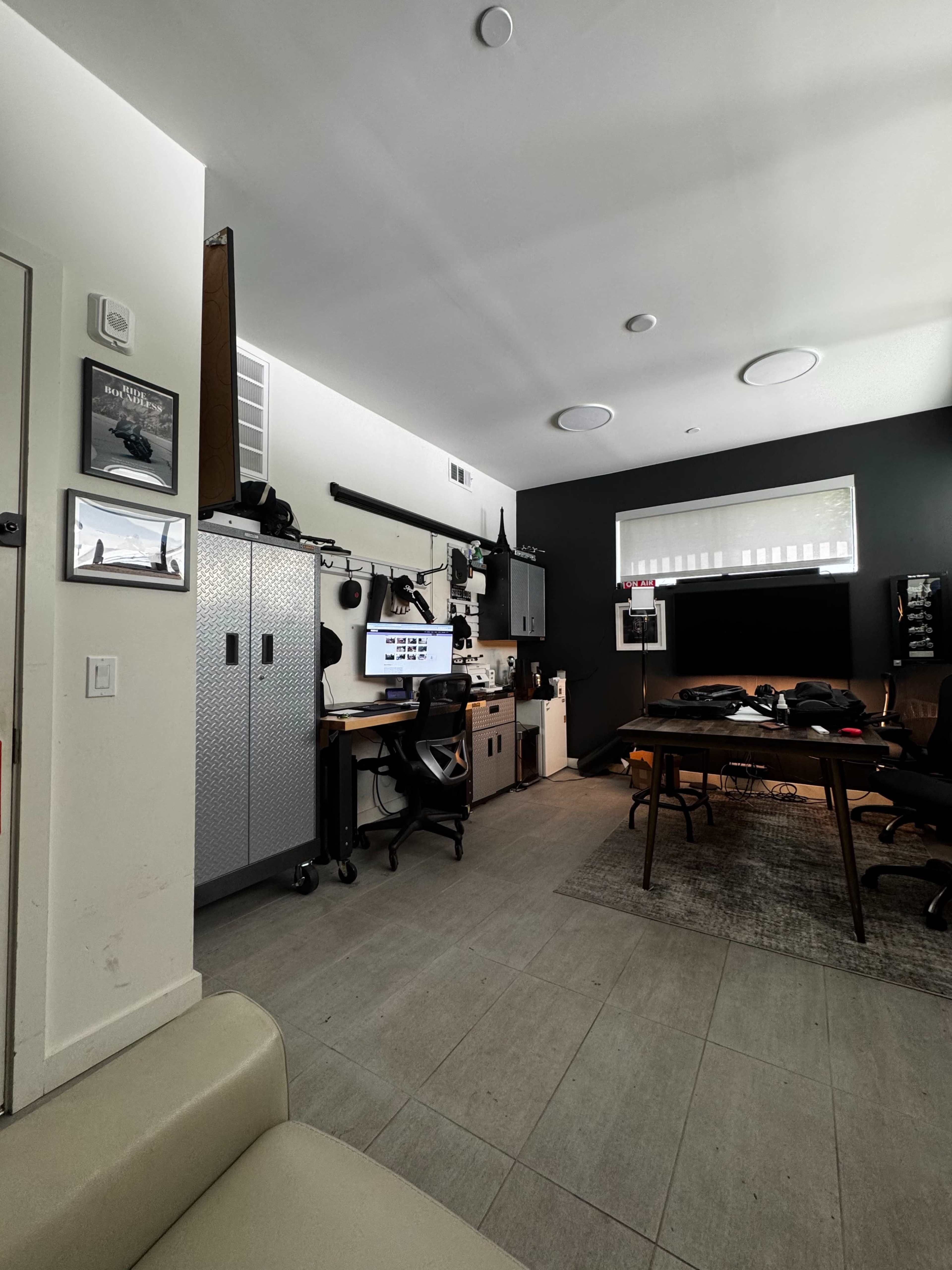 A modern office space featuring a desk with a computer, filing cabinets, and a meeting table surrounded by chairs.