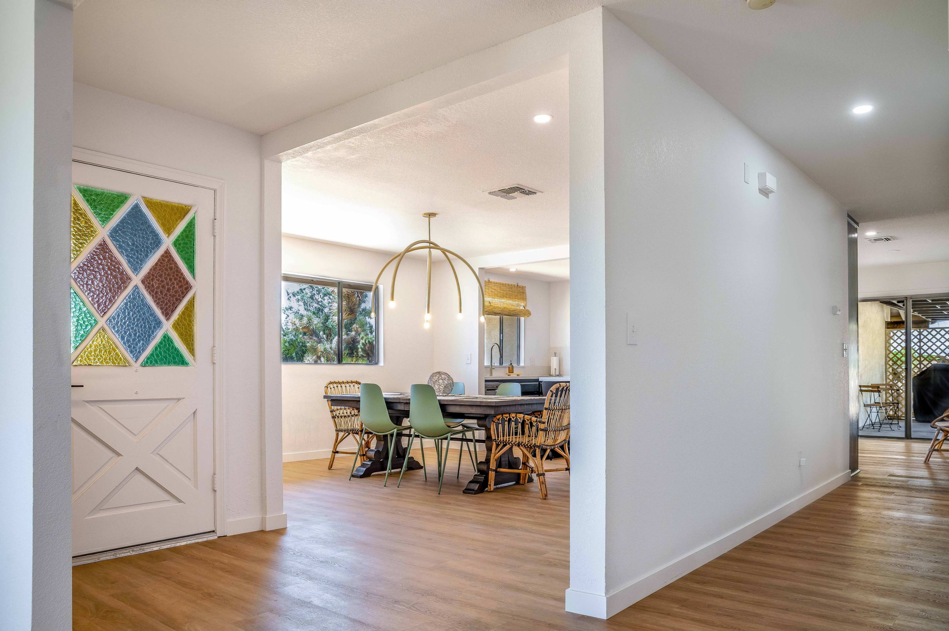 A hallway leads to a dining area featuring a circular table surrounded by chairs and a decorative light fixture.