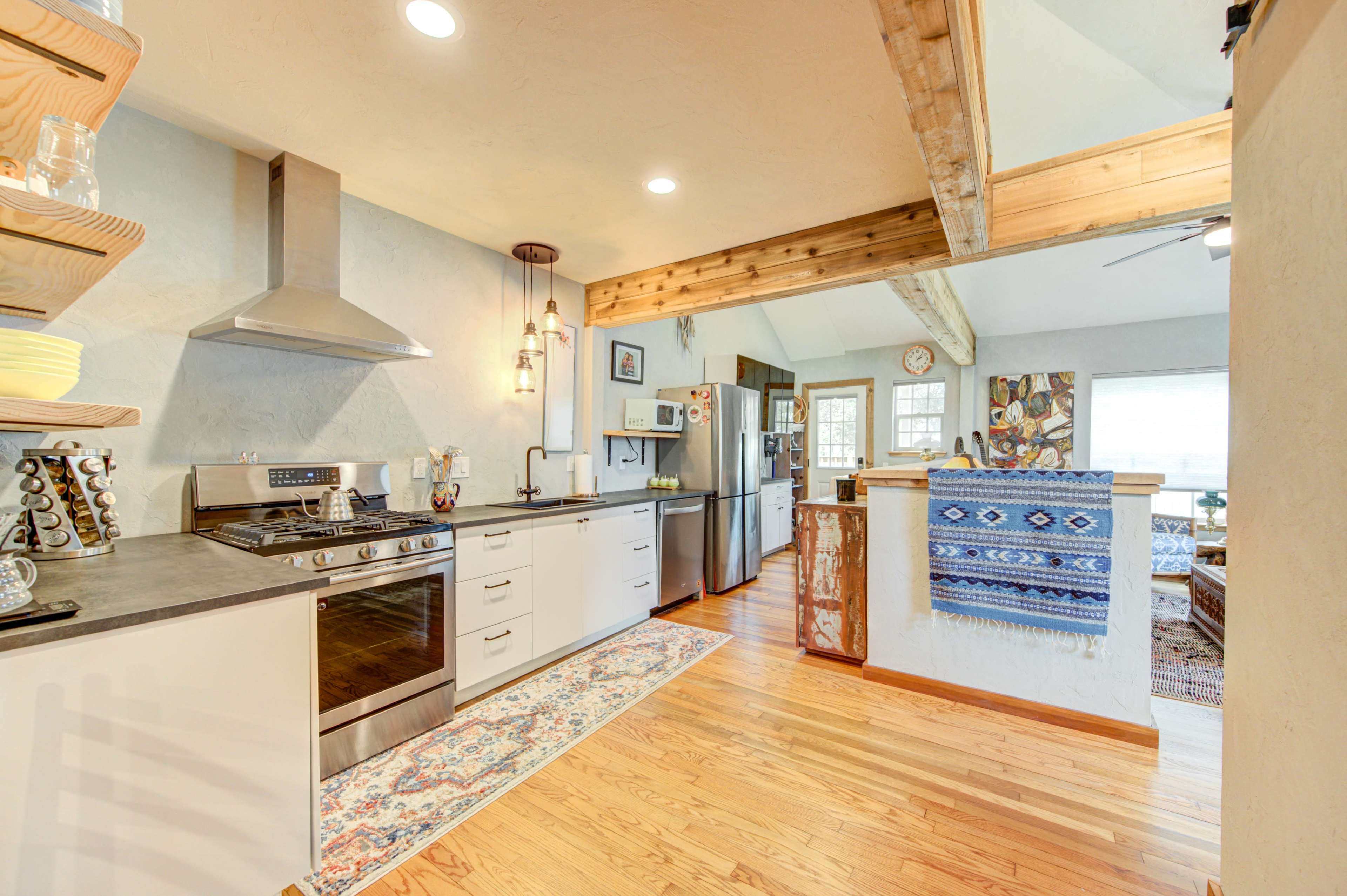 A modern kitchen with stainless steel appliances, wooden cabinetry, and an open layout that connects to a living area.