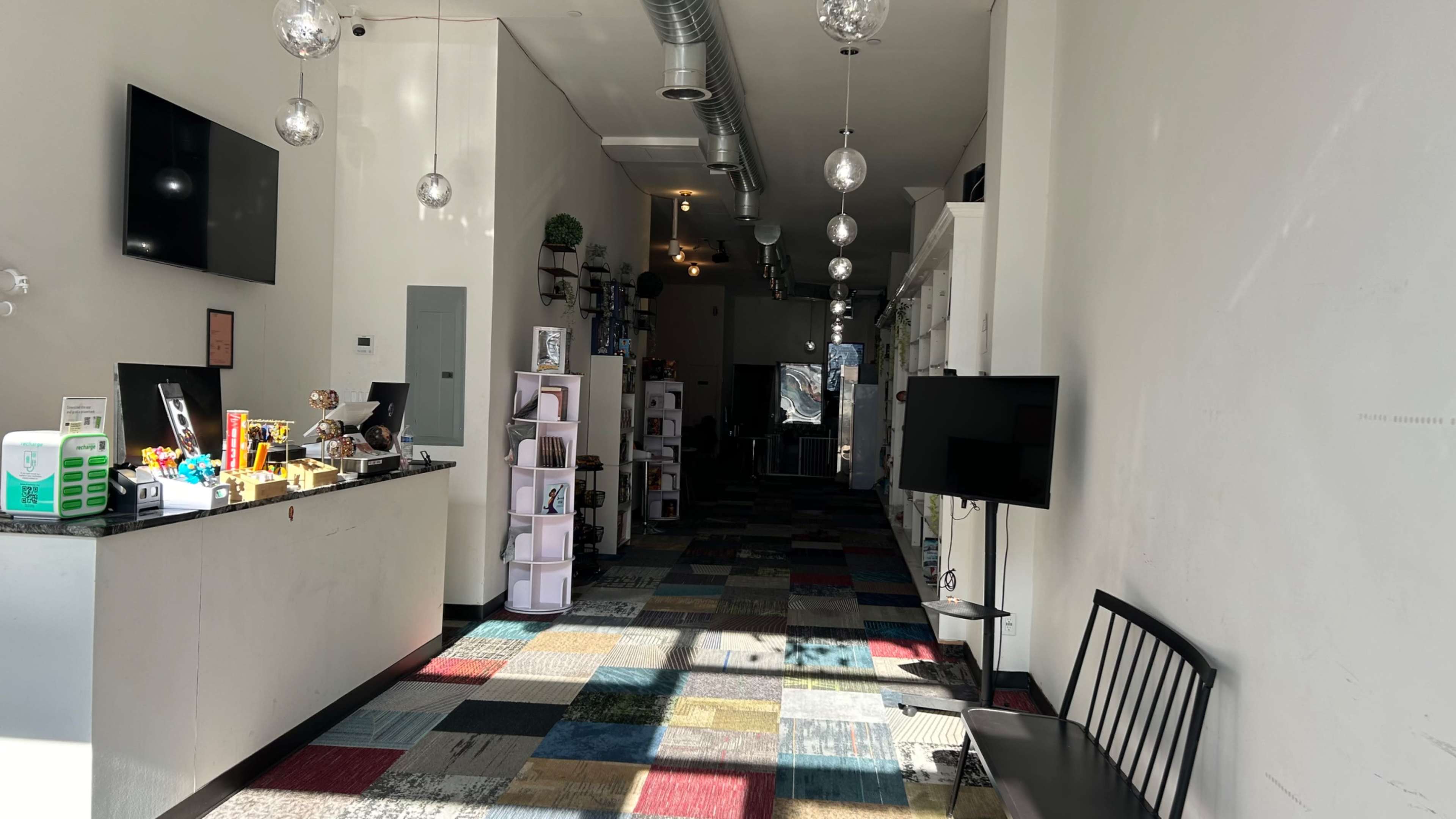 An interior space featuring a reception area with a counter on the left, colorful tiled flooring, and shelves displaying items along the right side.
