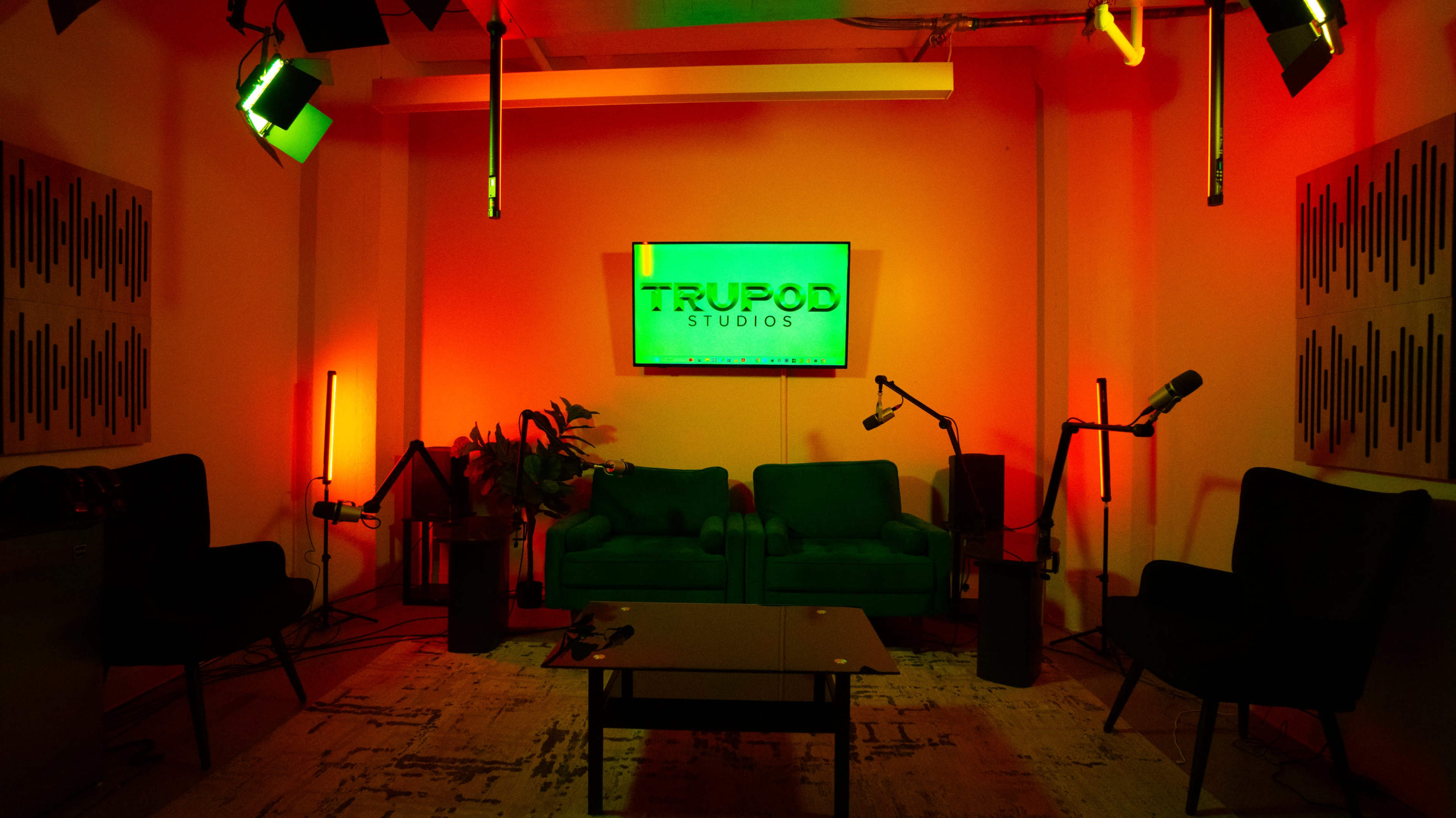The image shows a recording studio with green sofas, black chairs, and colorful lighting, featuring a screen labeled "TRUPOD STUDIOS."