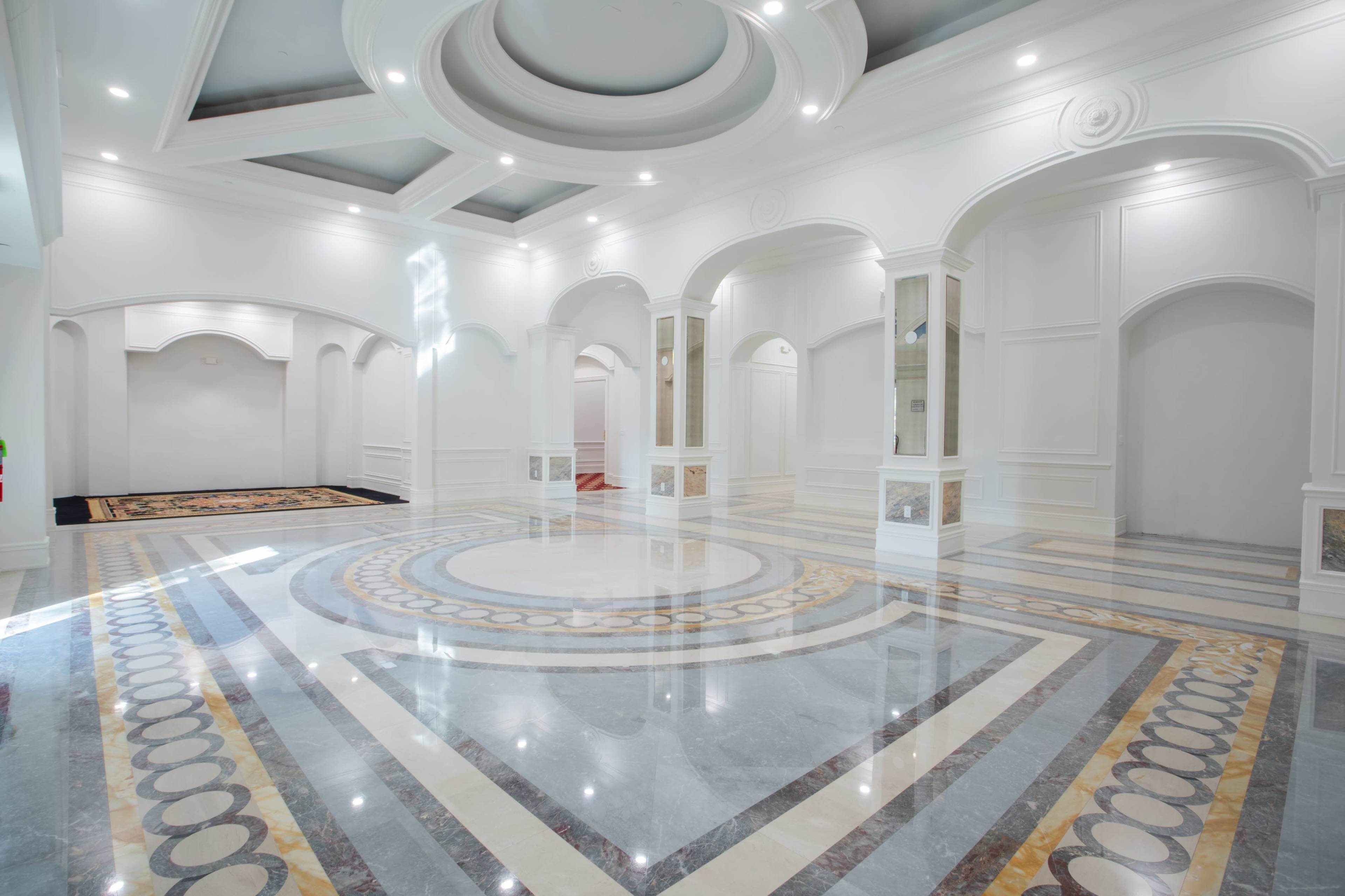 A spacious, elegantly designed interior with a polished marble floor featuring circular patterns and several archways.