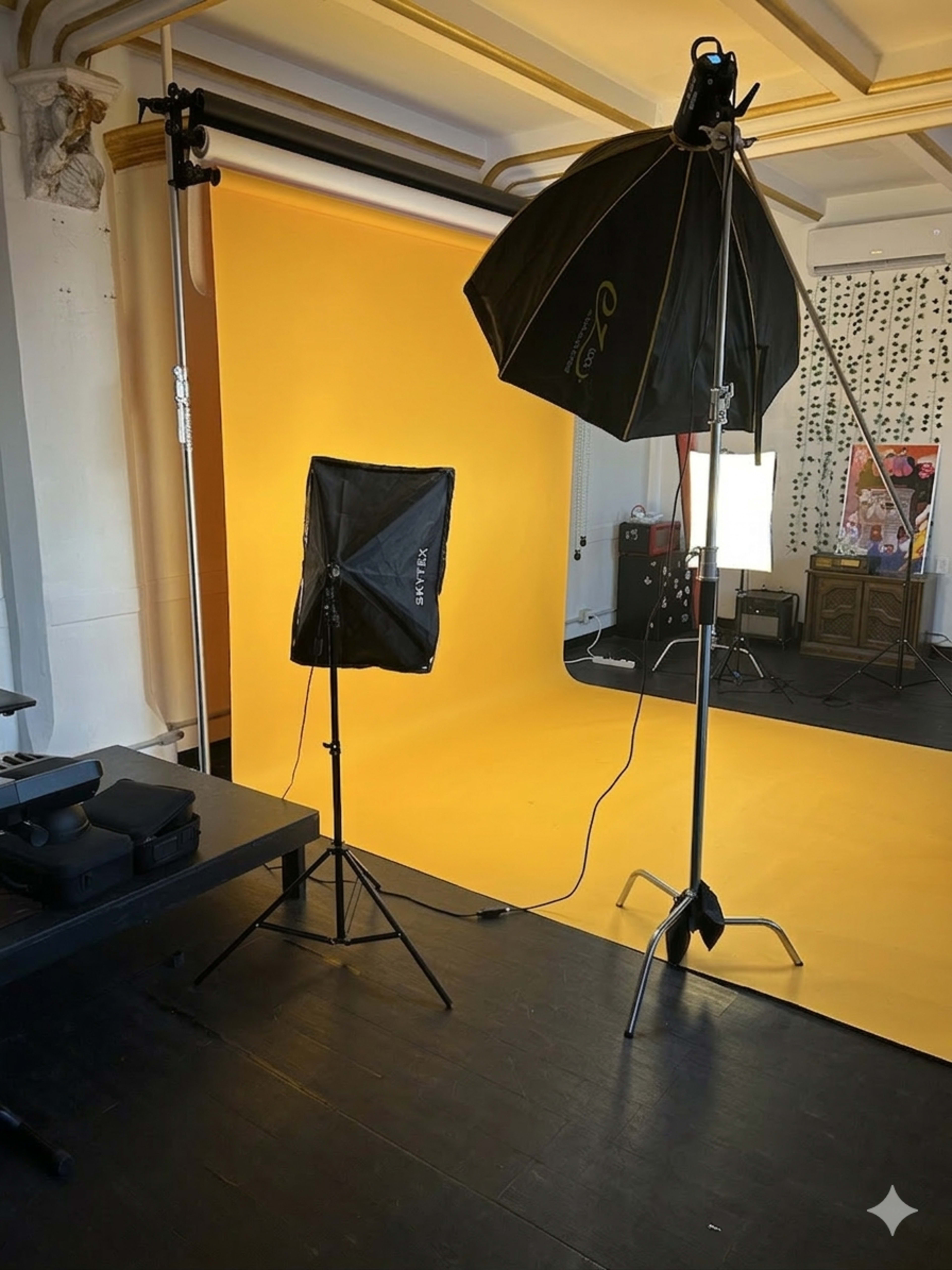 The scene shows a photography studio with a bright yellow backdrop, lighting equipment, and a dark floor.