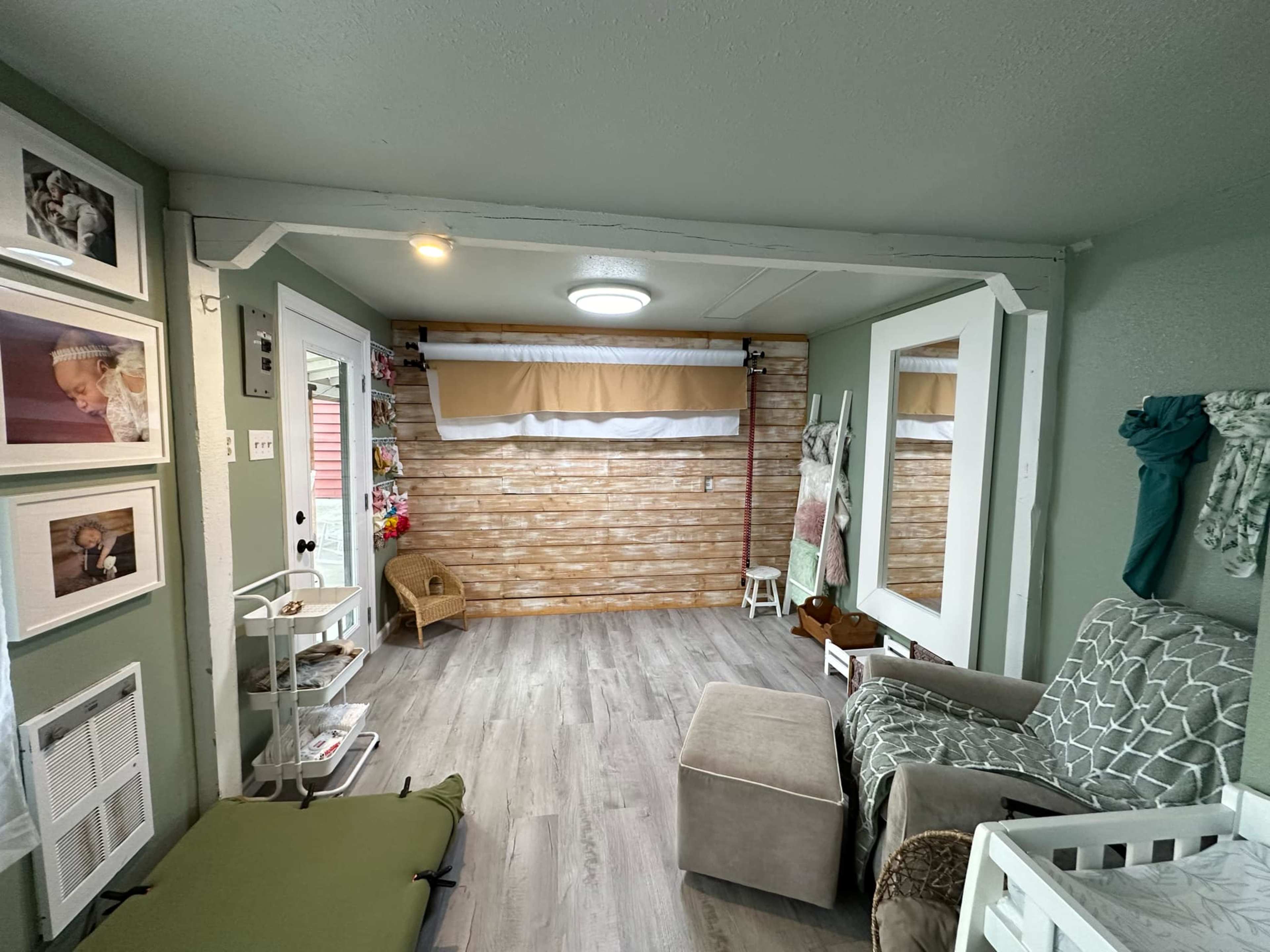 The interior of a small, light-colored living space features a wooden accent wall, a comfortable seating area, and various decor elements.