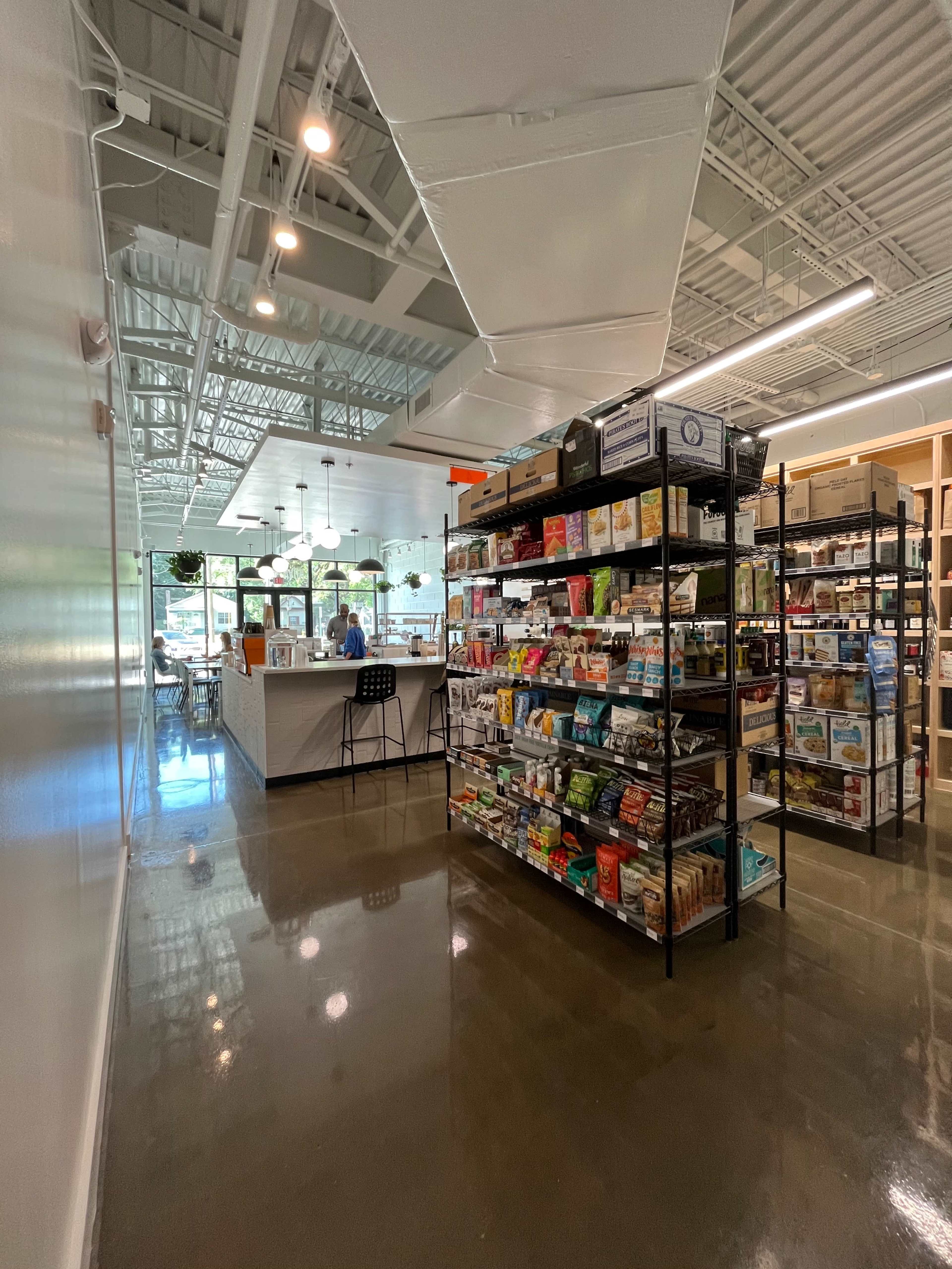A spacious interior of a store featuring neatly organized shelves filled with various products and a counter area in the background.