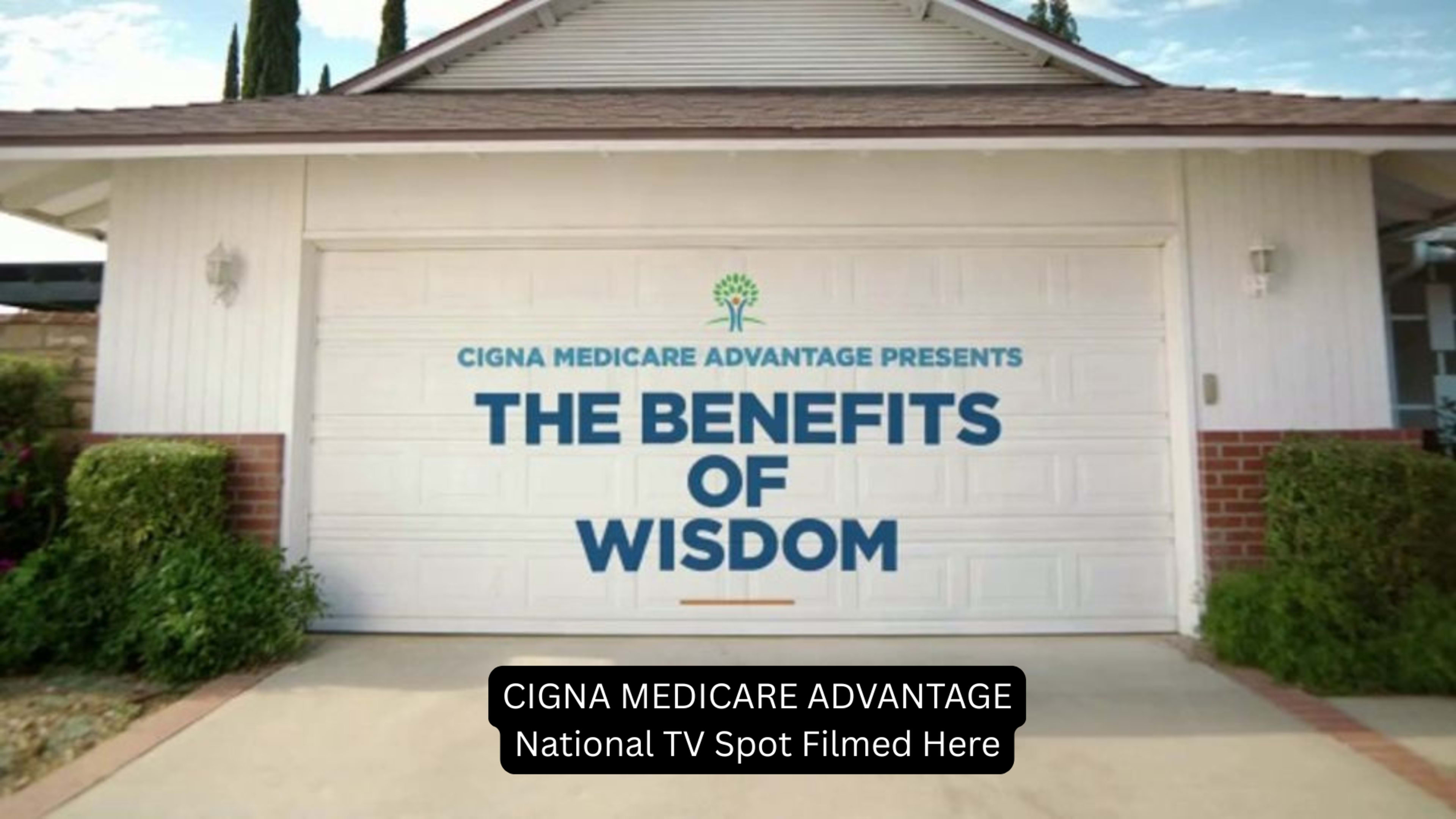 A garage door displays a promotional message for Cigna Medicare Advantage, highlighting "The Benefits of Wisdom."