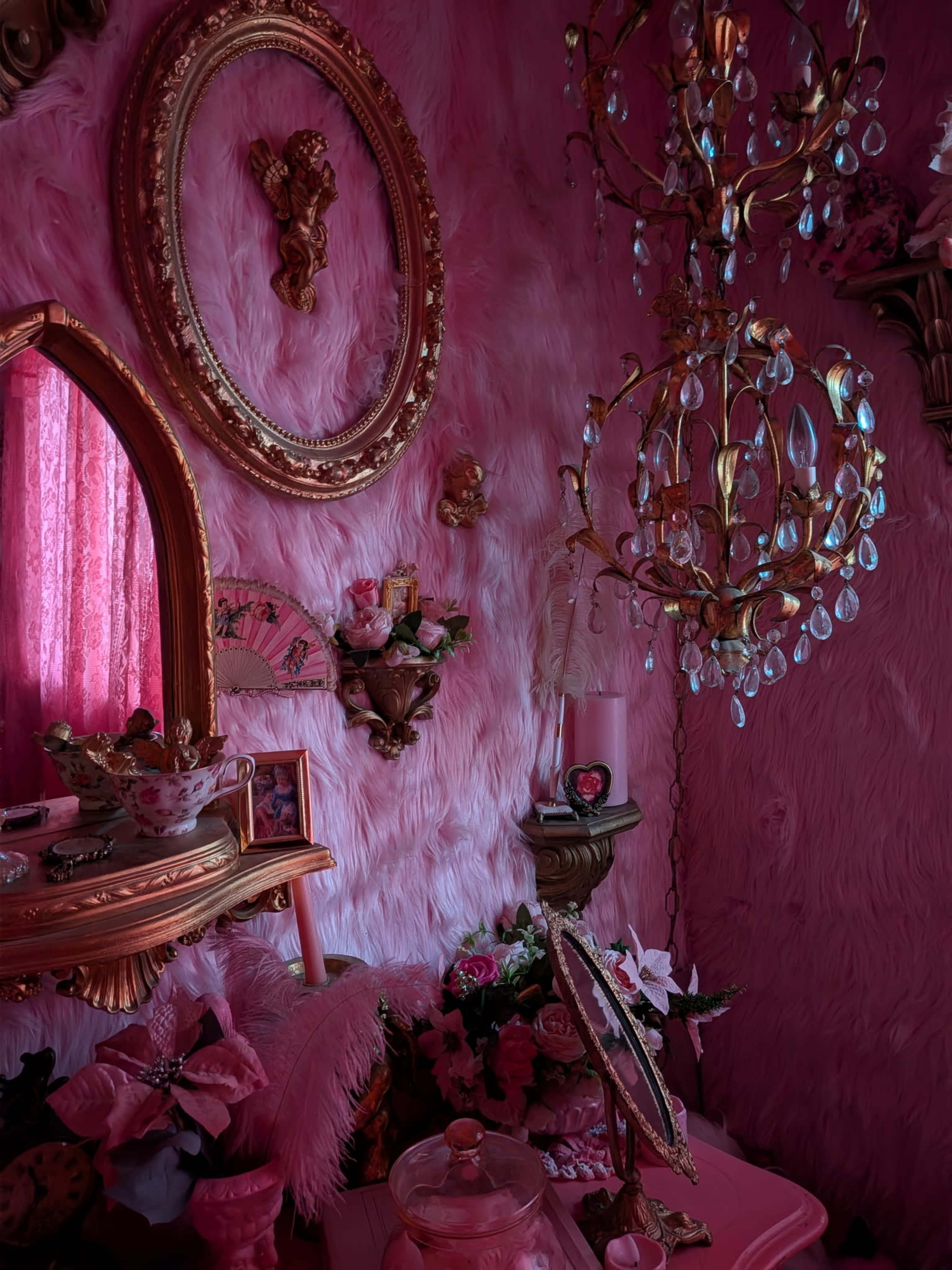 The scene features a pink-themed room with plush walls, ornate decor, and a chandelier, alongside various framed mirrors and floral arrangements.