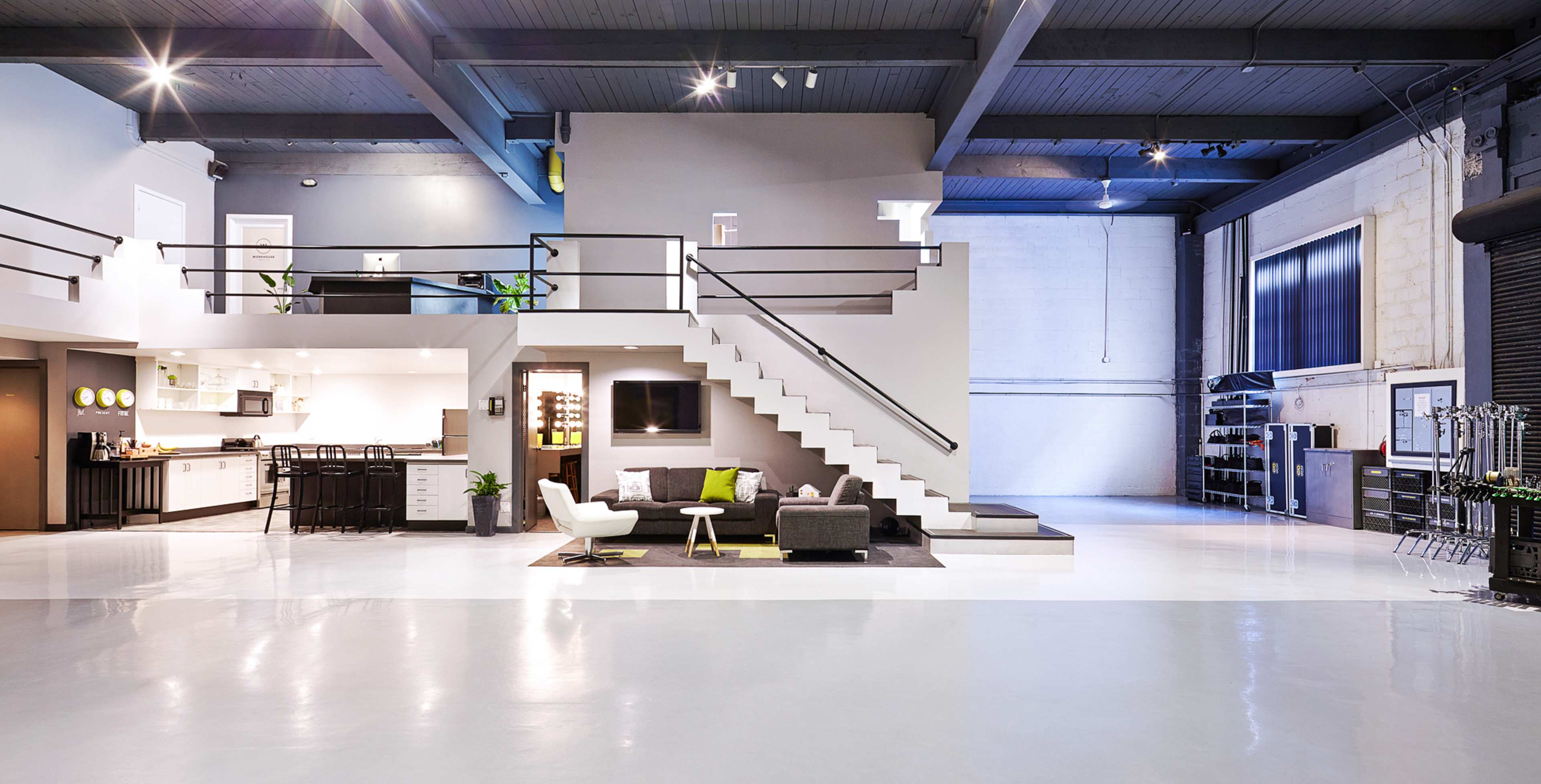 A spacious, modern open-concept living area with a kitchen, a staircase, and various seating arrangements.