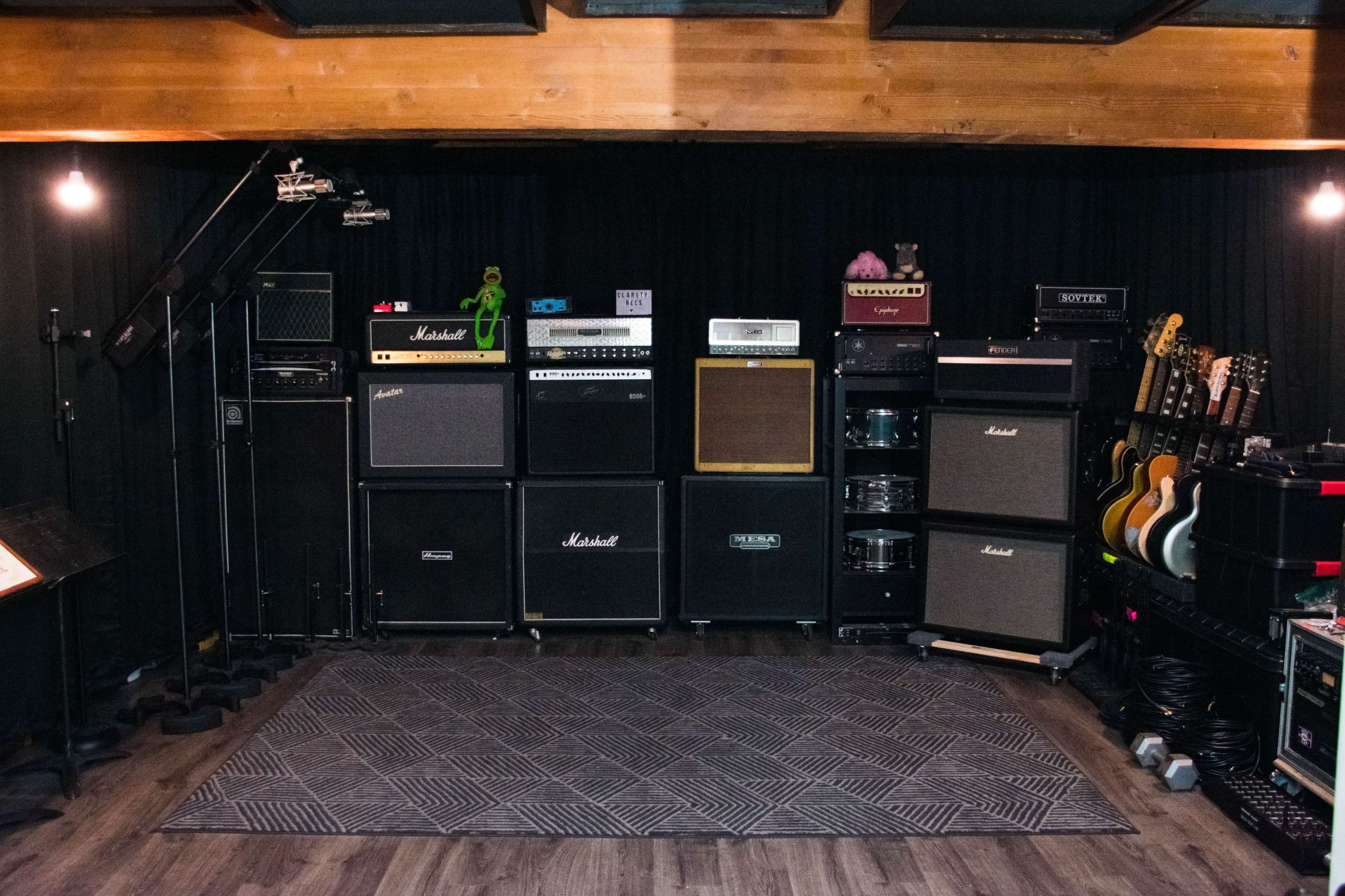 A music studio setup with various amplifiers and electric guitars arranged along a wall.
