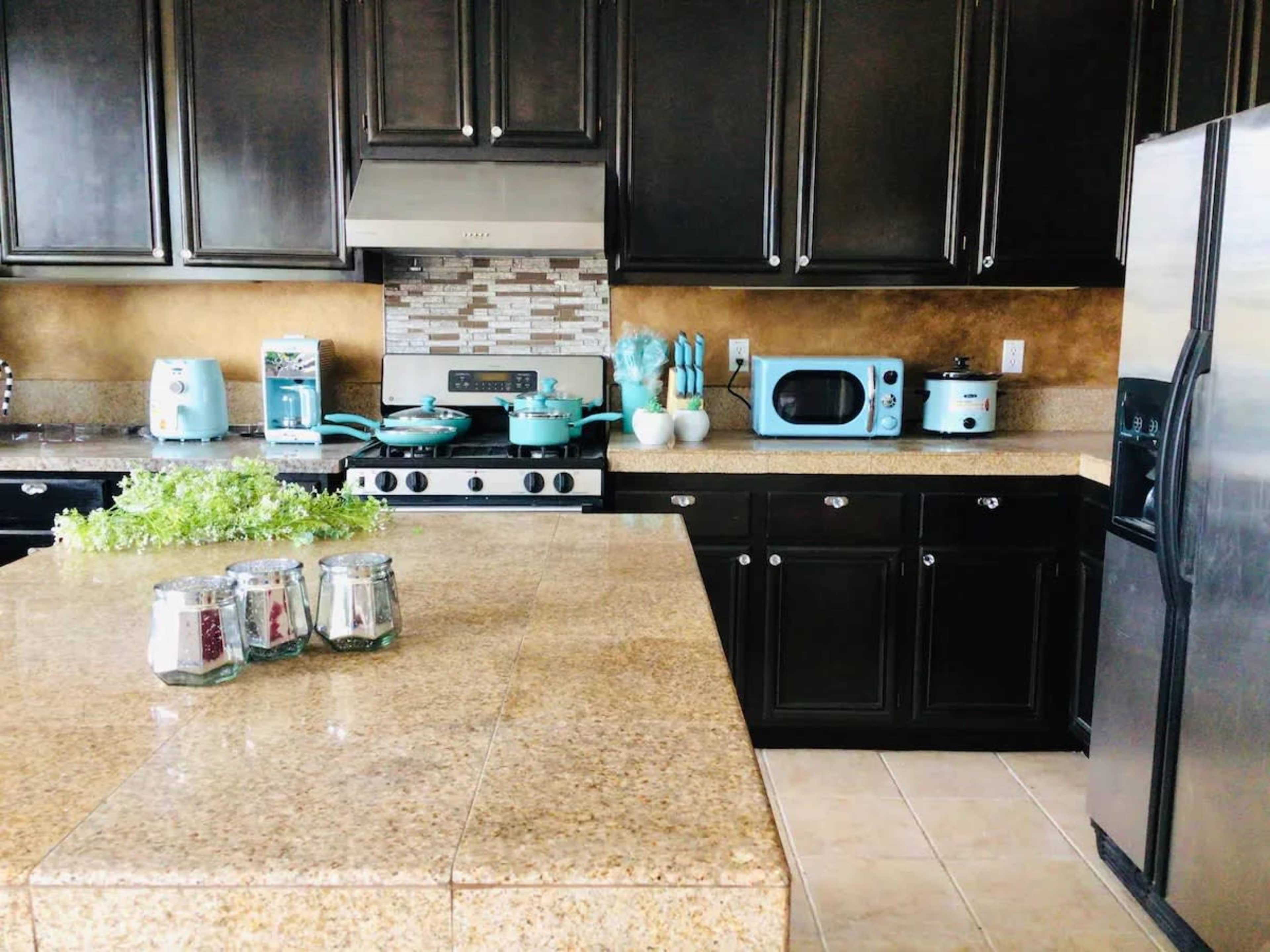 The kitchen features dark cabinets, a granite countertop, and vintage-style turquoise appliances against a tiled backsplash.