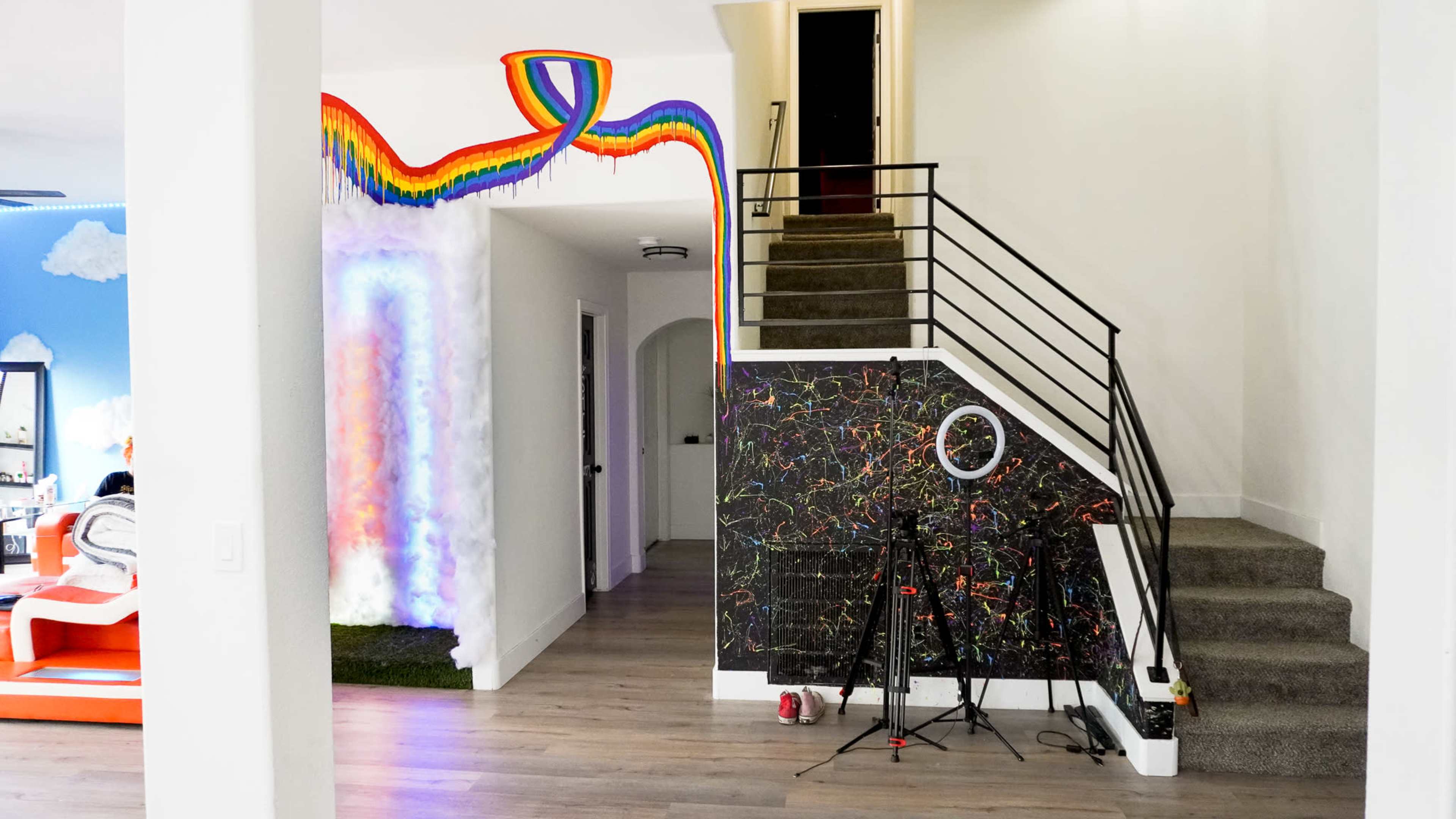 An interior space featuring a staircase, a colorful mural with a rainbow, and some equipment set up on the floor.