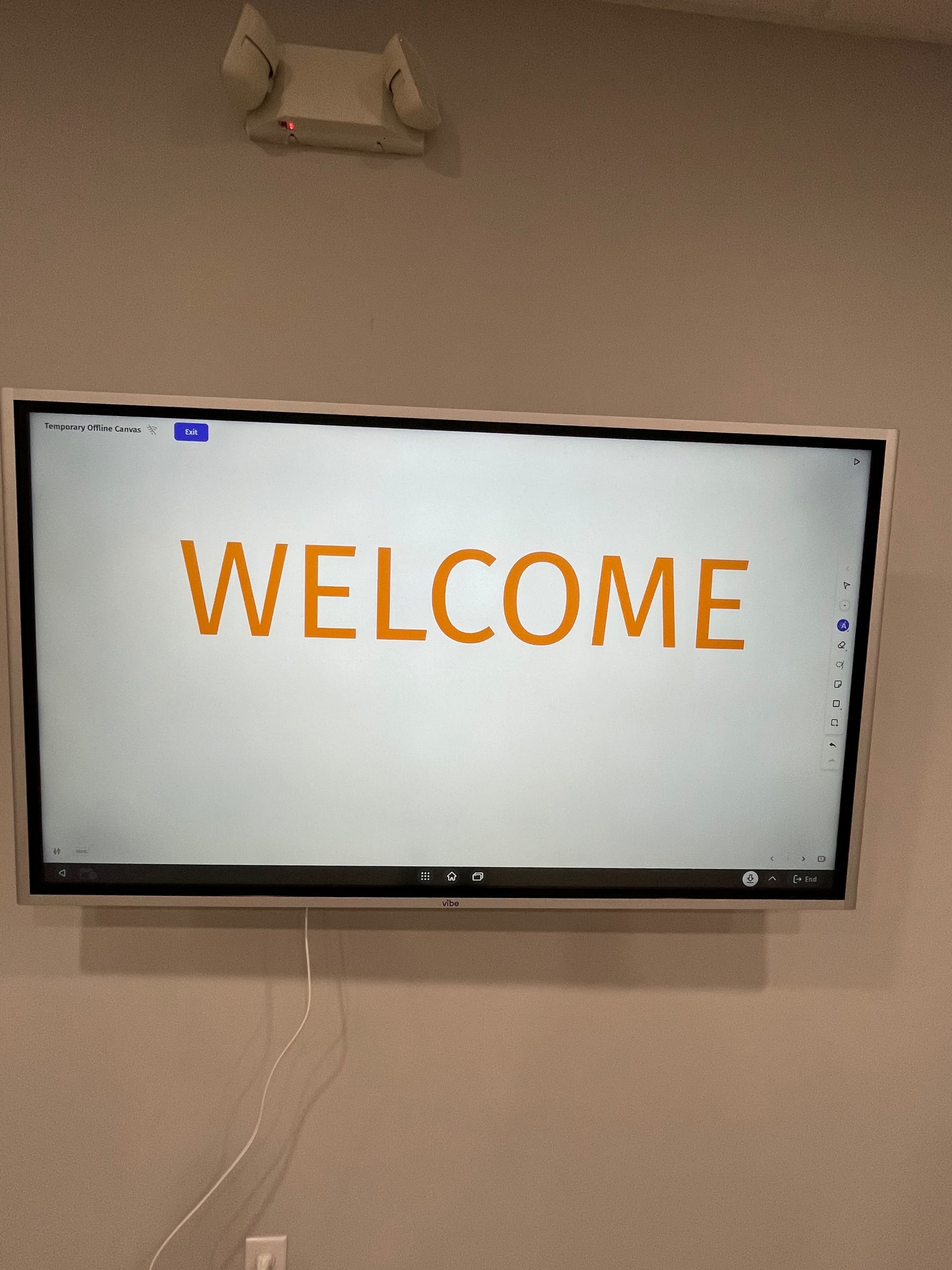 A large screen displays the word "WELCOME" in orange letters on a plain background.