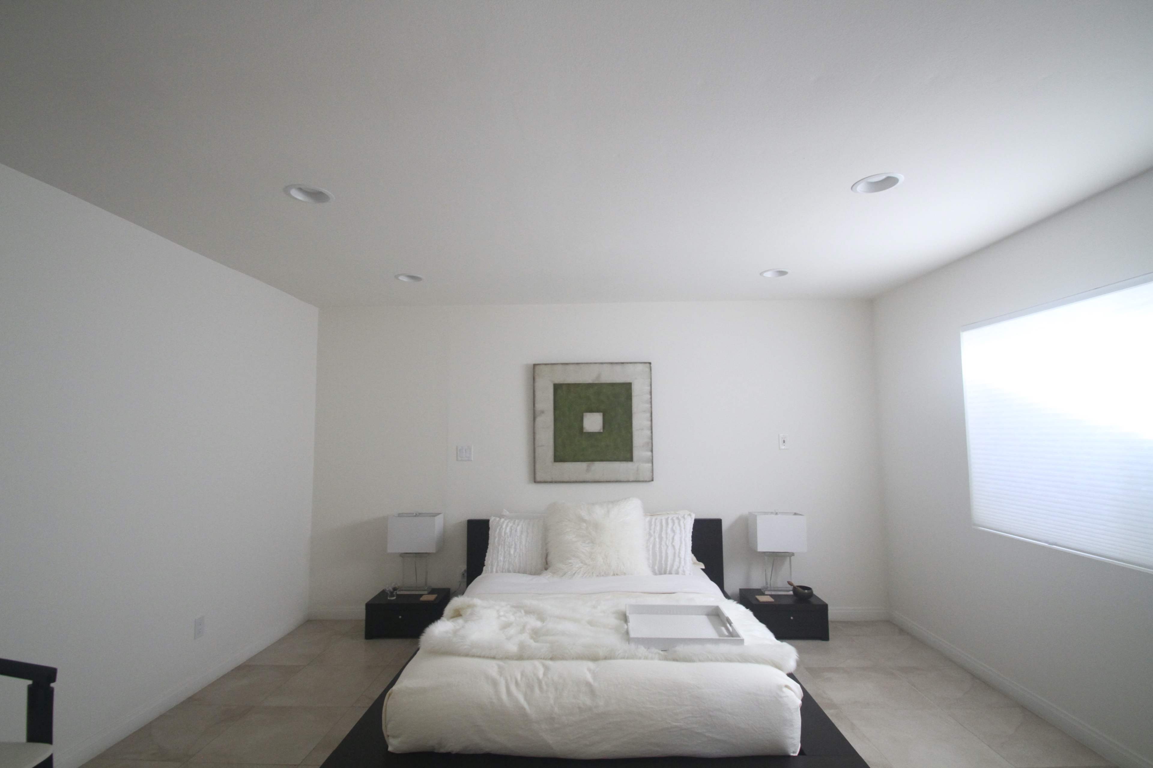 A minimalist bedroom with a bed, two nightstands, and a window allowing natural light.
