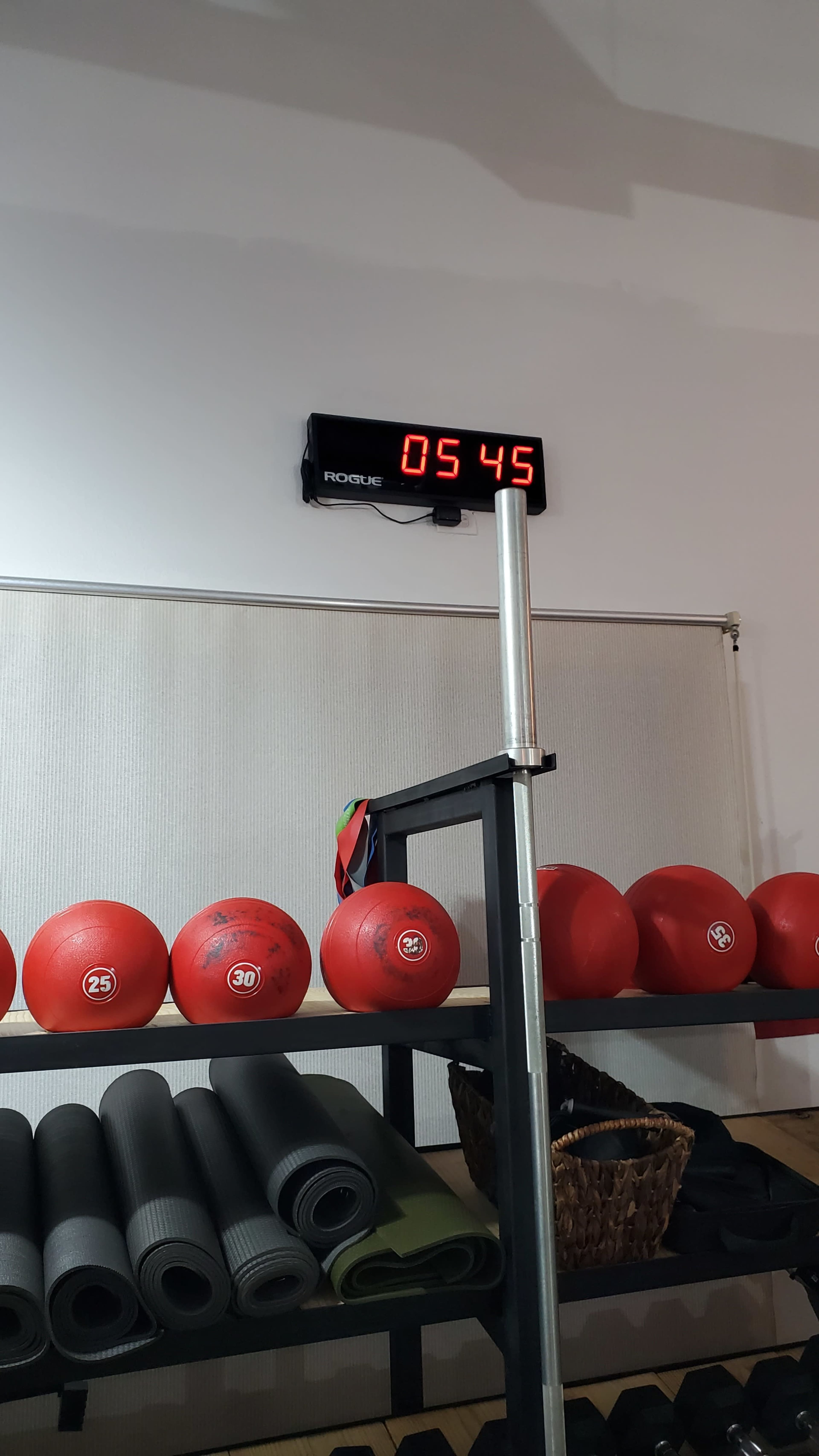 A fitness storage rack with red workout balls numbered 25 and 30, along with a digital timer displaying 05:45.