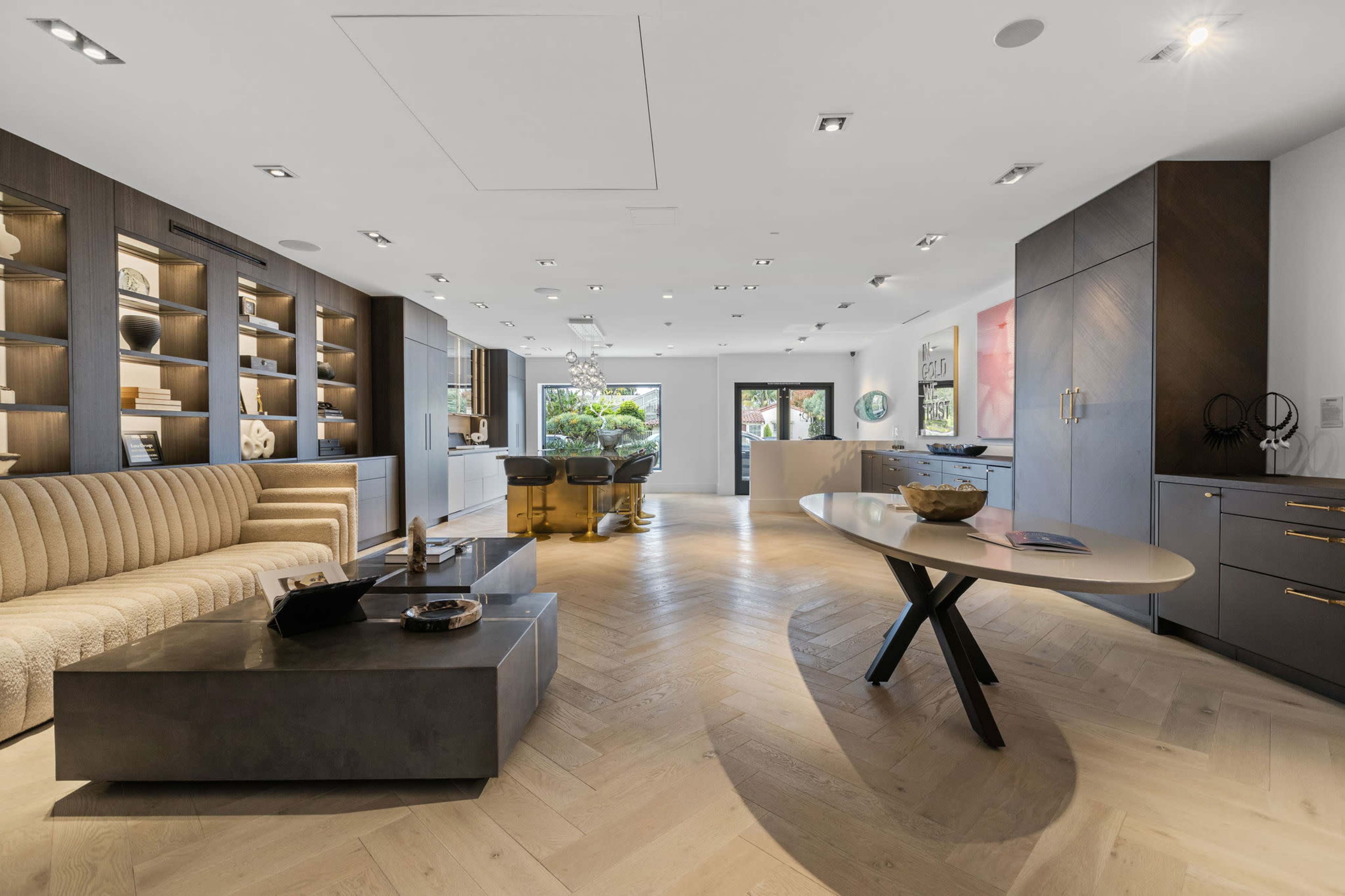 A modern interior space featuring a stylish living area with a beige sofa, a sleek coffee table, and a well-lit design with shelves displaying decorative items.