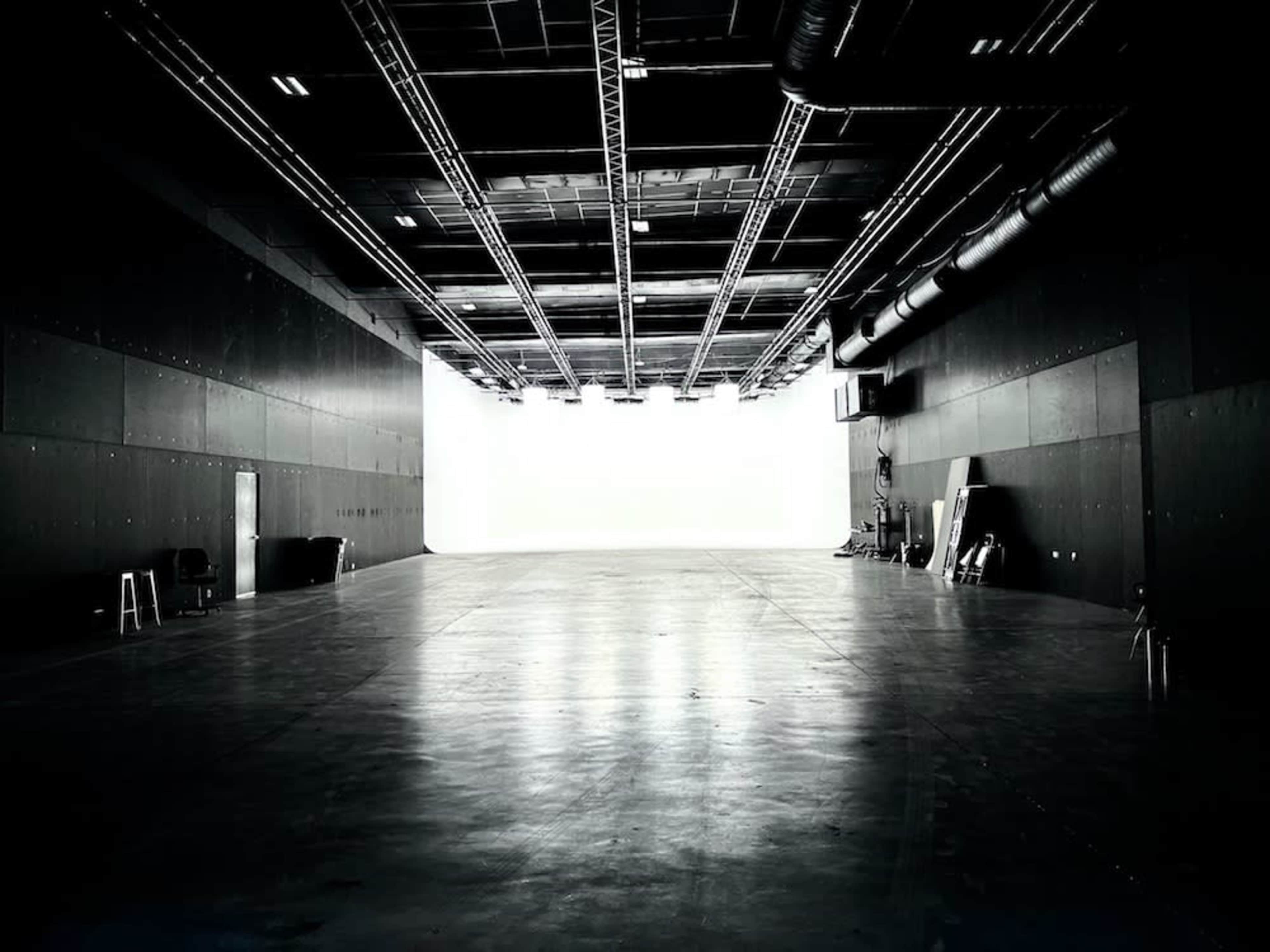 A large, empty studio space with bright light at one end and dark walls.