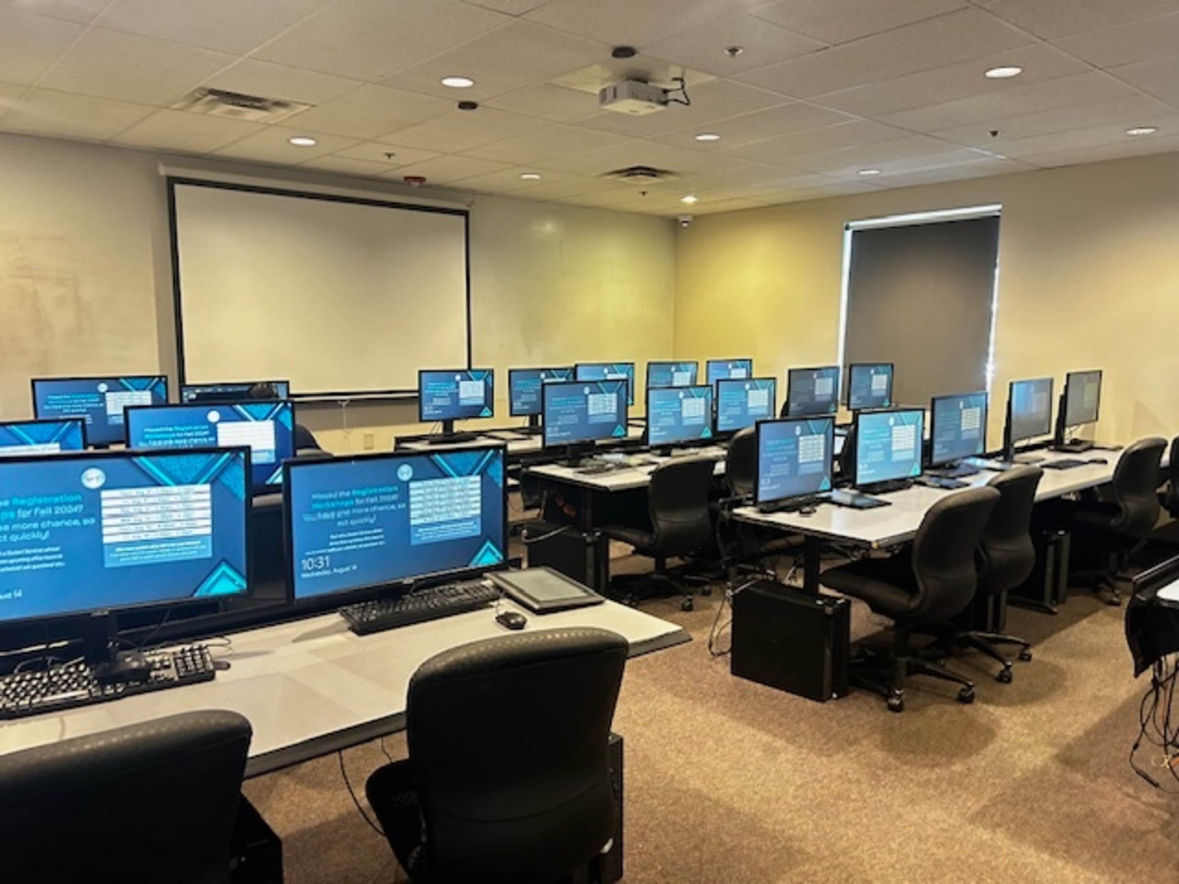 A classroom equipped with multiple computer workstations arranged in rows, each displaying similar digital content on their screens.