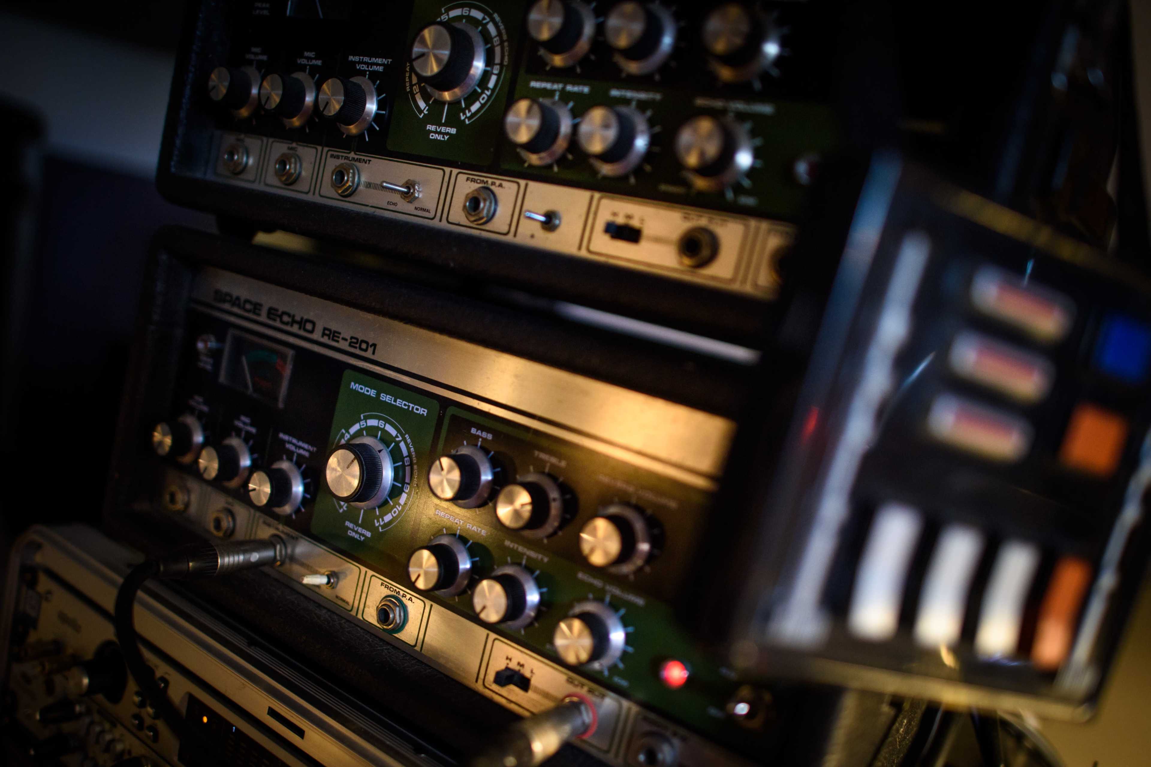 The image shows a close-up of vintage audio equipment, featuring multiple knobs and controls on a tape echo machine.