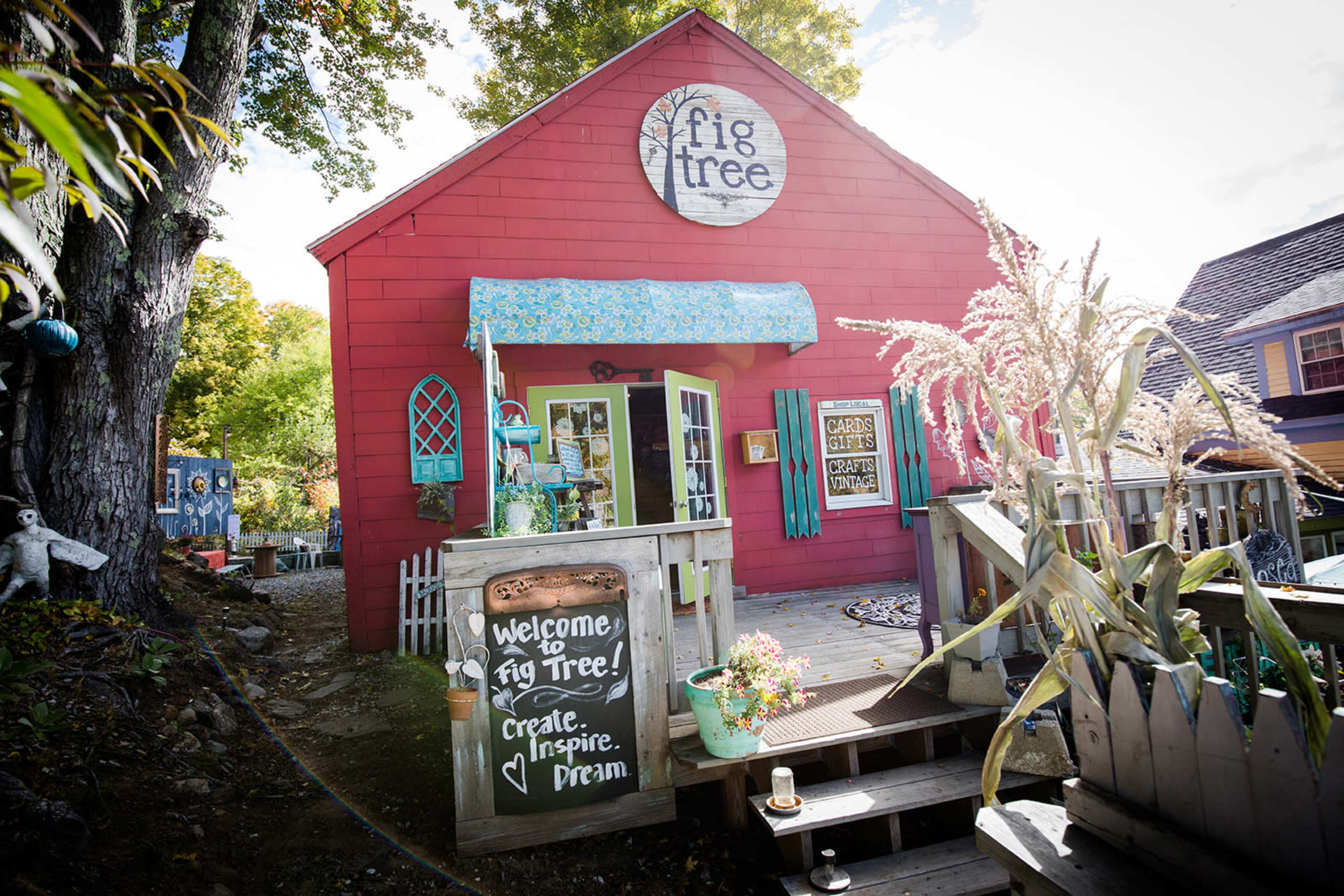The image shows a red building with a sign that reads "Fig Tree," featuring a welcoming entrance and outdoor decorations.