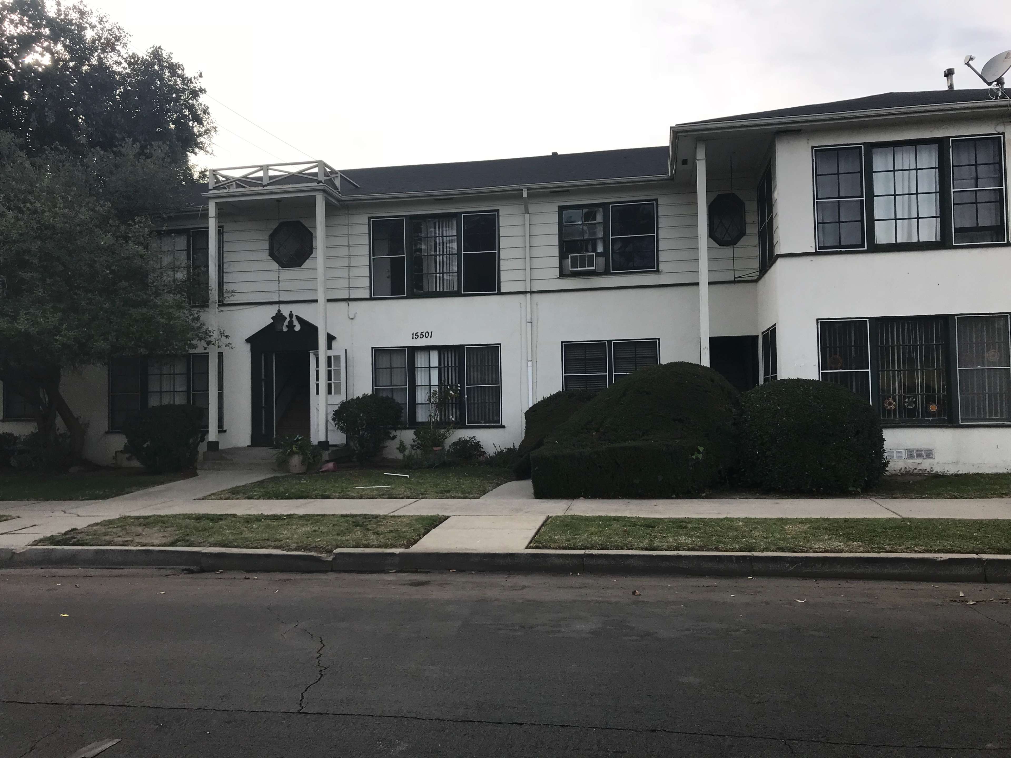 A two-story residential building with a front lawn and sidewalk is shown.