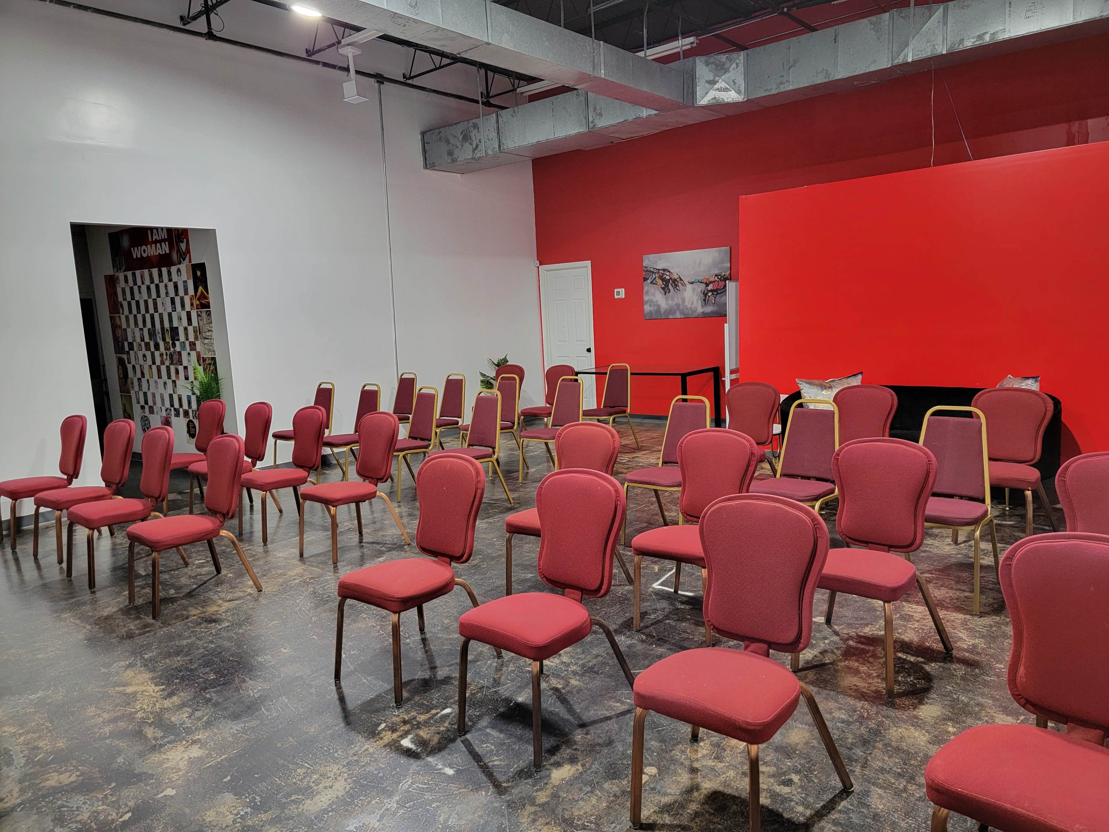 A room filled with rows of red upholstered chairs arranged for an event.