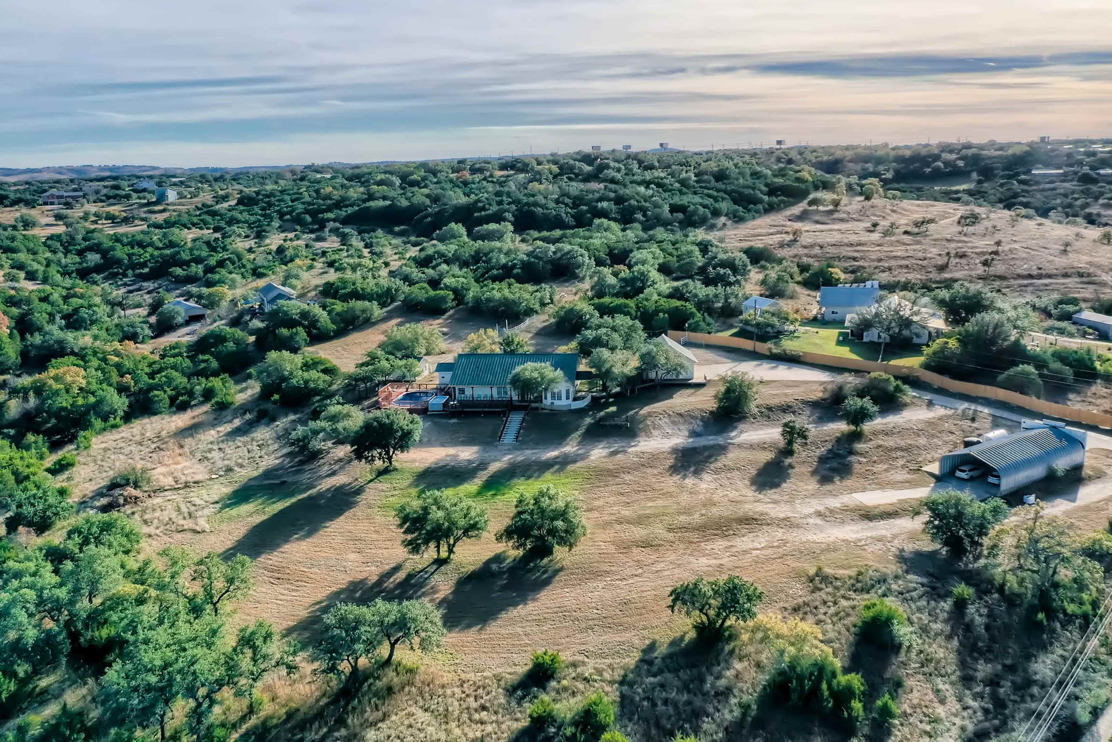 An aerial view captures a rural landscape featuring several homes surrounded by trees and open fields.