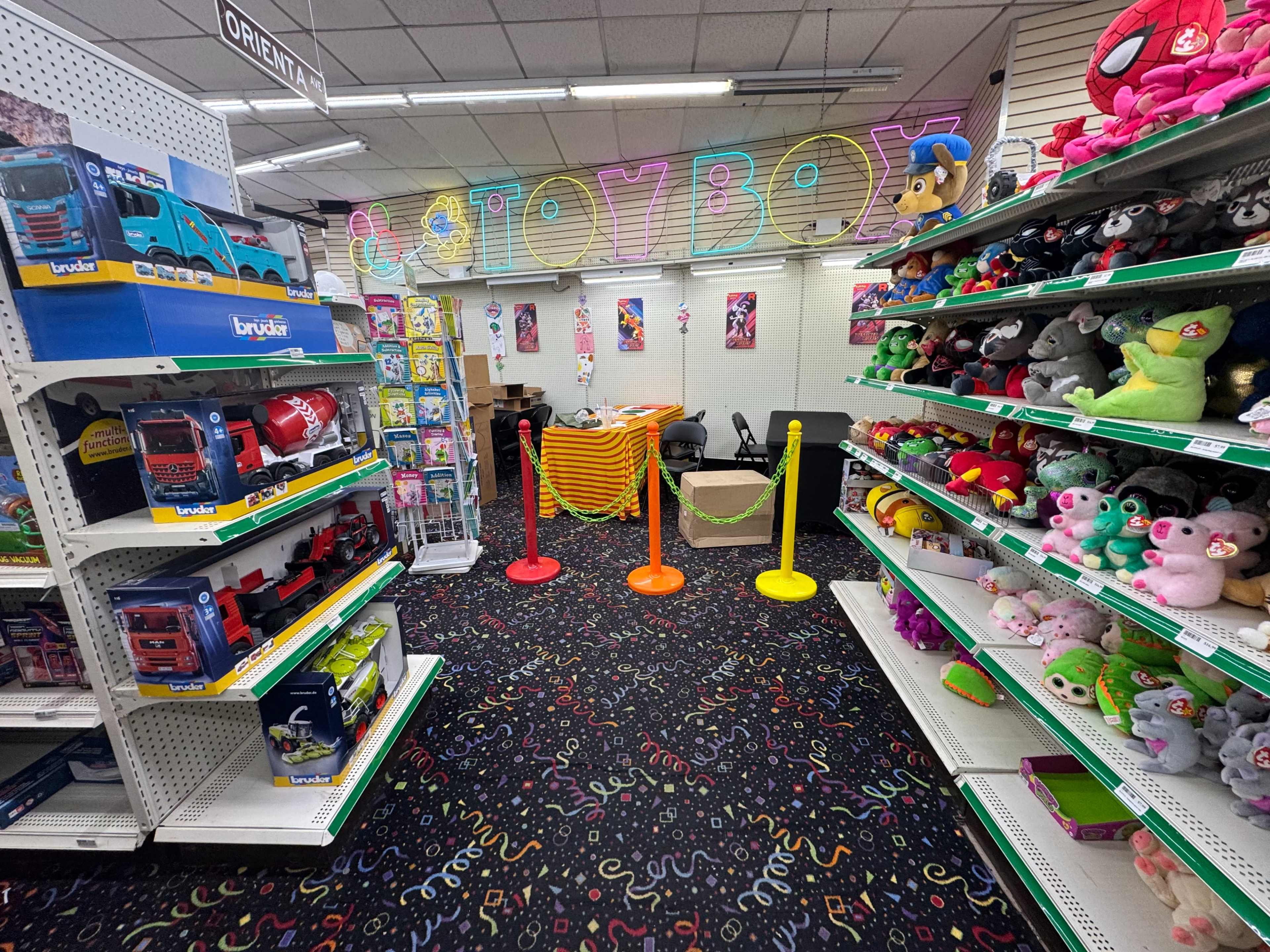 The image shows the interior of a toy store with colorful shelves filled with toys, plush animals, and a sectioned-off area marked by barriers.