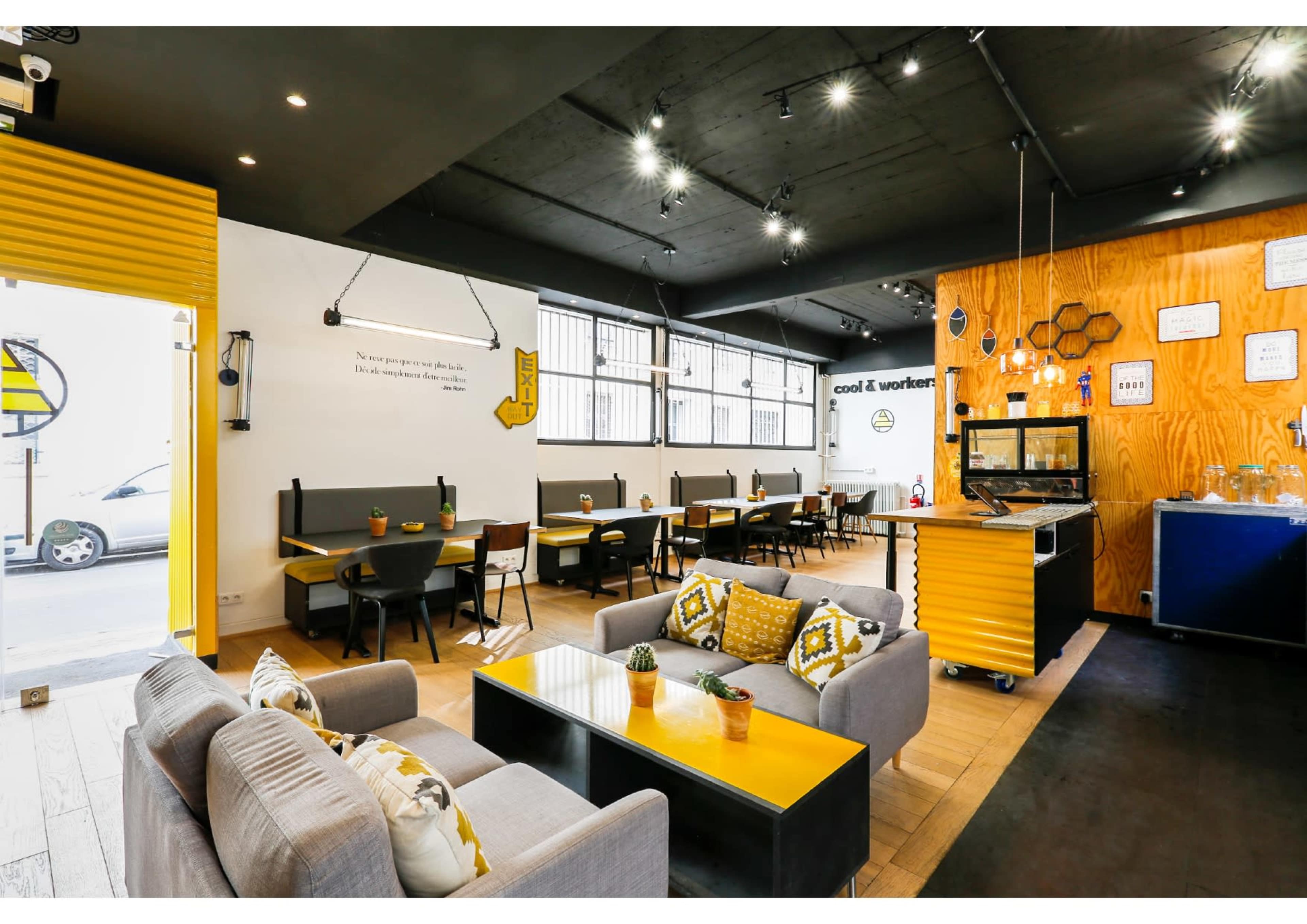 A modern café interior with seating areas, a service counter, and decor featuring wooden panels and bright yellow accents.