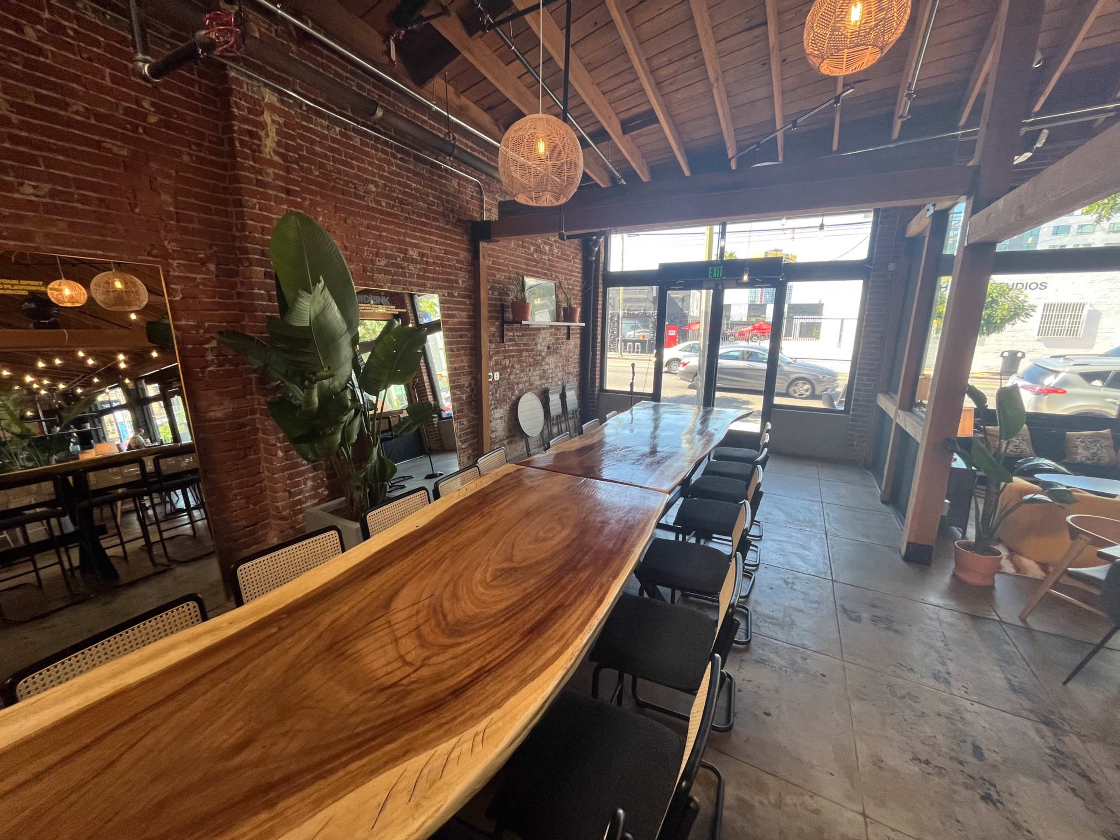 A dining area with a large wooden table, surrounded by chairs, exposed brick walls, and pendant lighting.