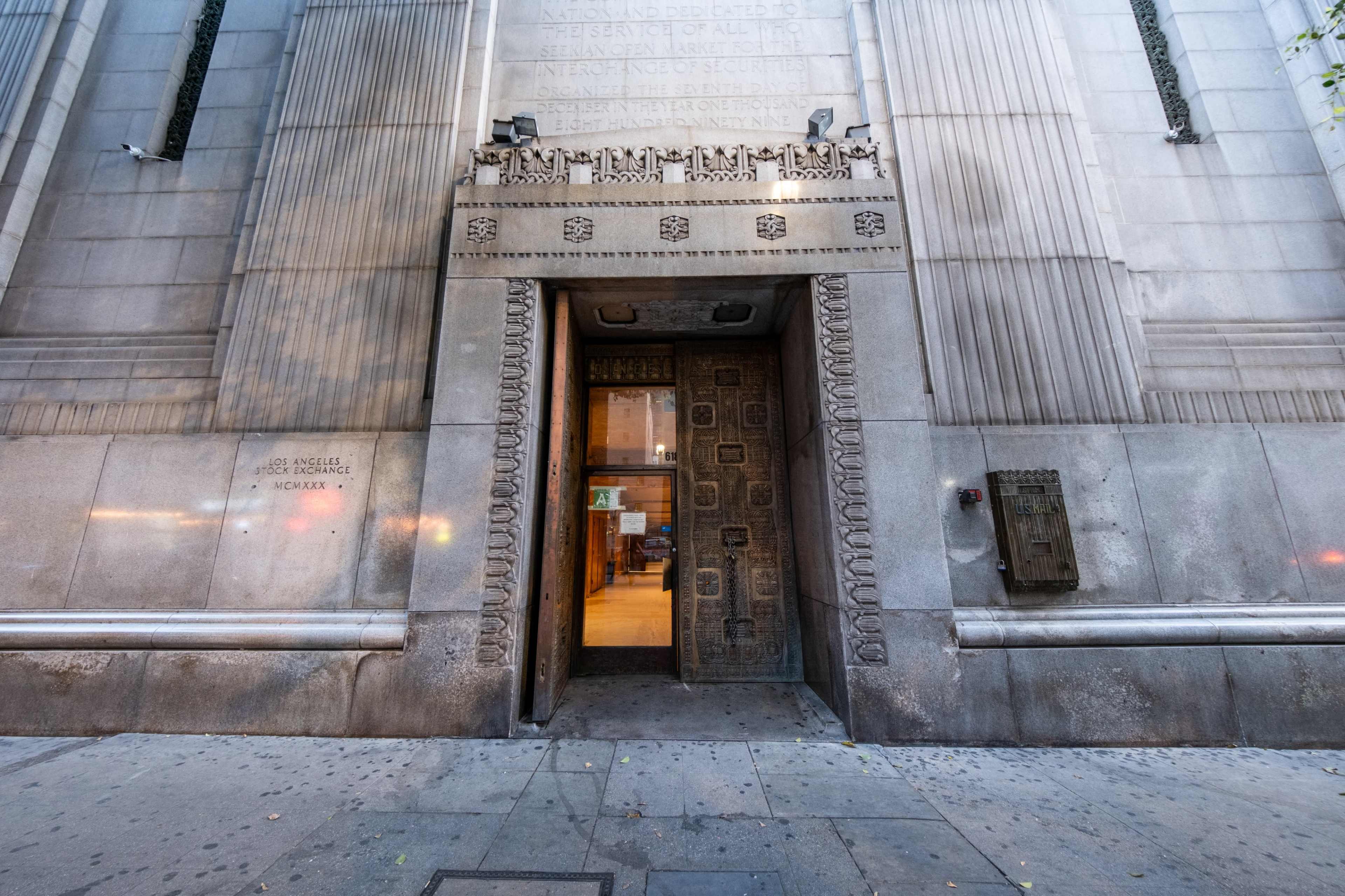 The ornate entrance of a historic building, featuring decorative stonework and an open door revealing indoor lighting.