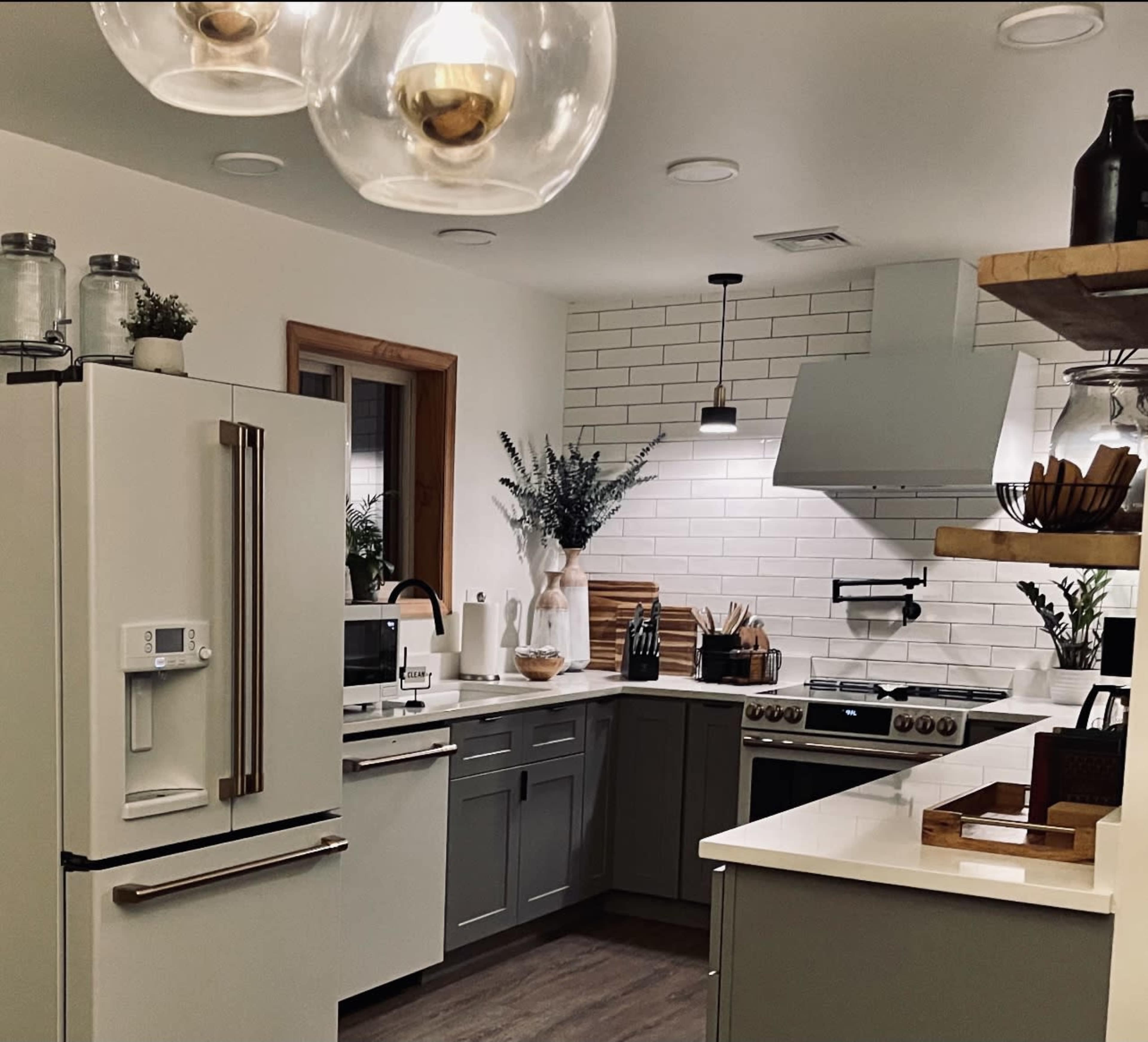 A modern kitchen featuring gray cabinets, a white countertop, stainless steel appliances, and a tile backsplash.