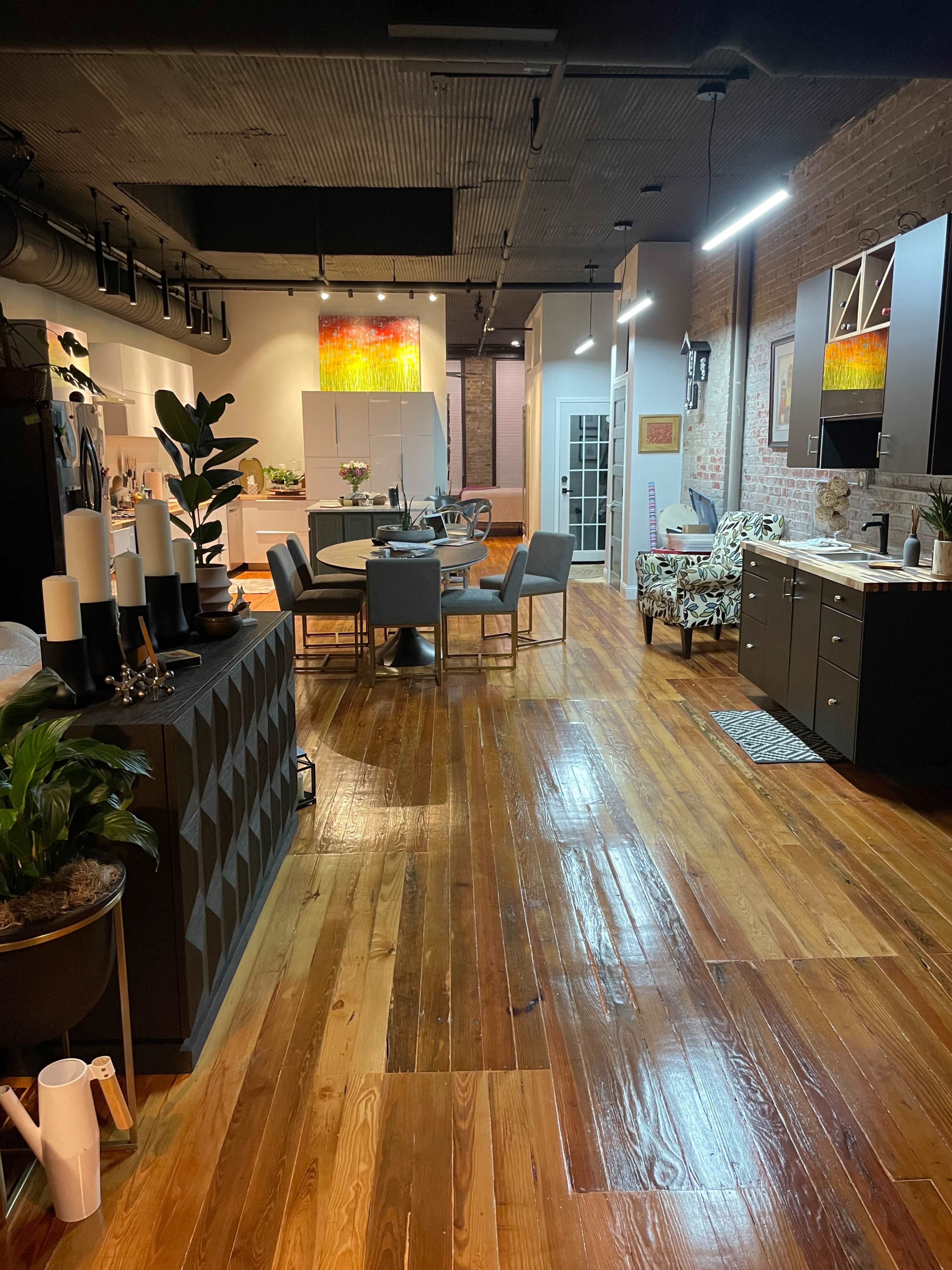 A spacious, modern open-concept apartment with hardwood floors, featuring a living area, dining space, and kitchen.