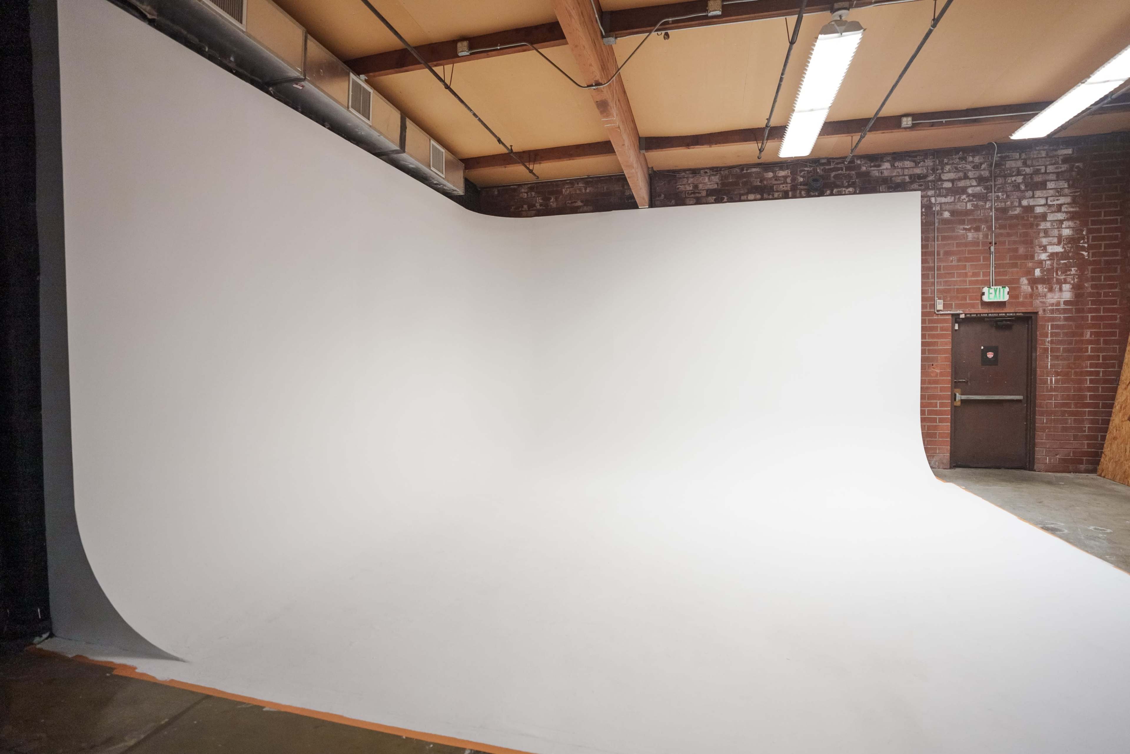 A photography studio with a seamless white backdrop and brick walls.