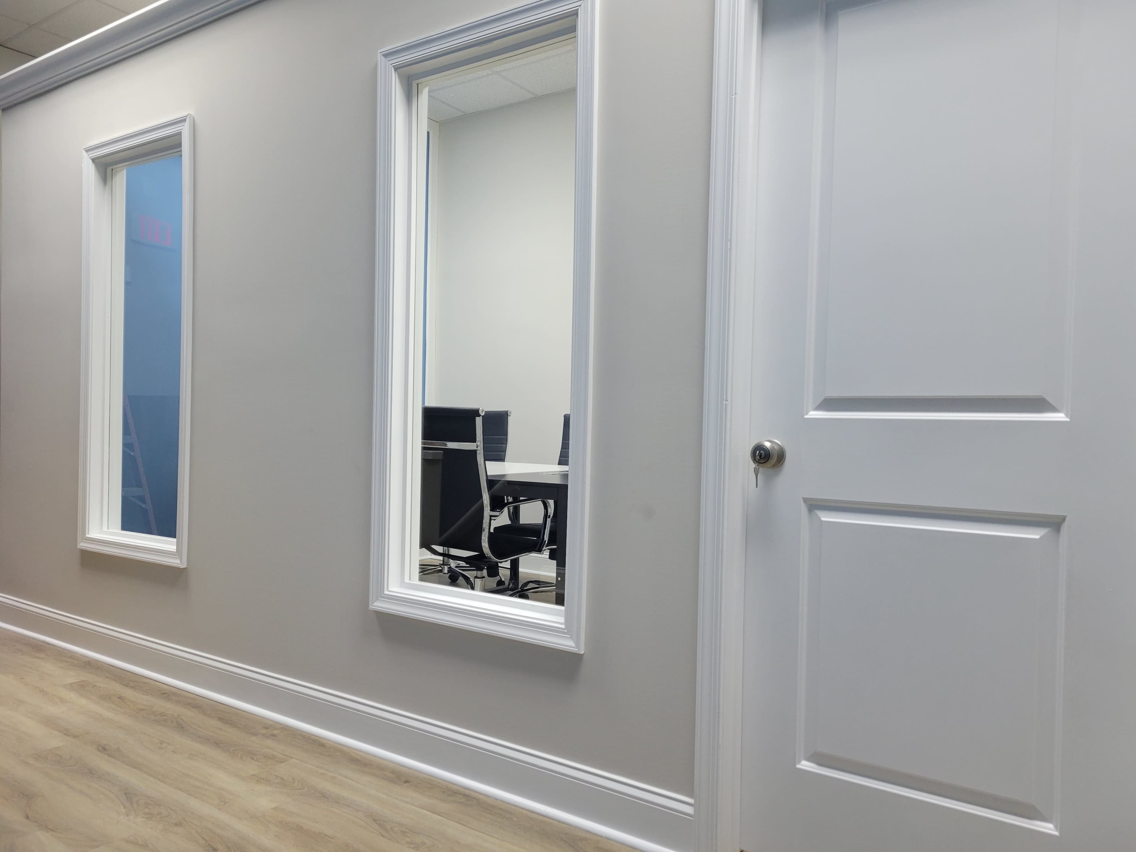 A hallway with two framed mirrors and a closed door leading to an office area.