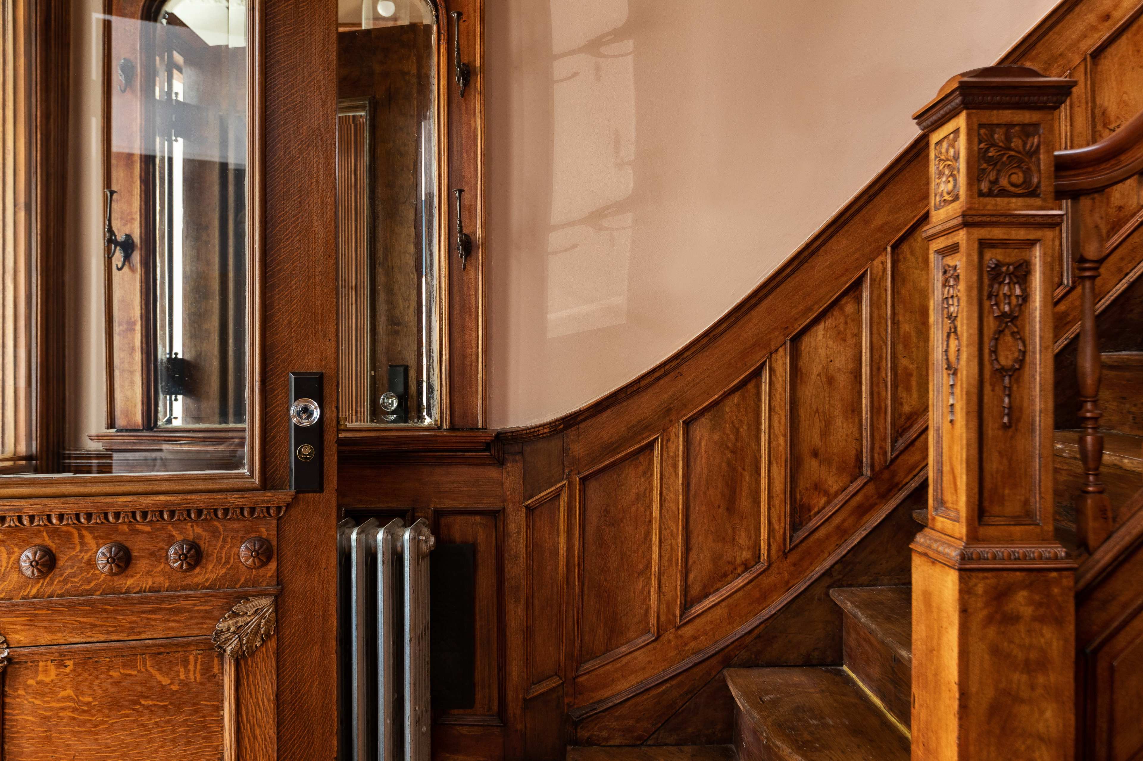 A wooden staircase leading up, adjacent to a glass-paneled door with intricate detailing.