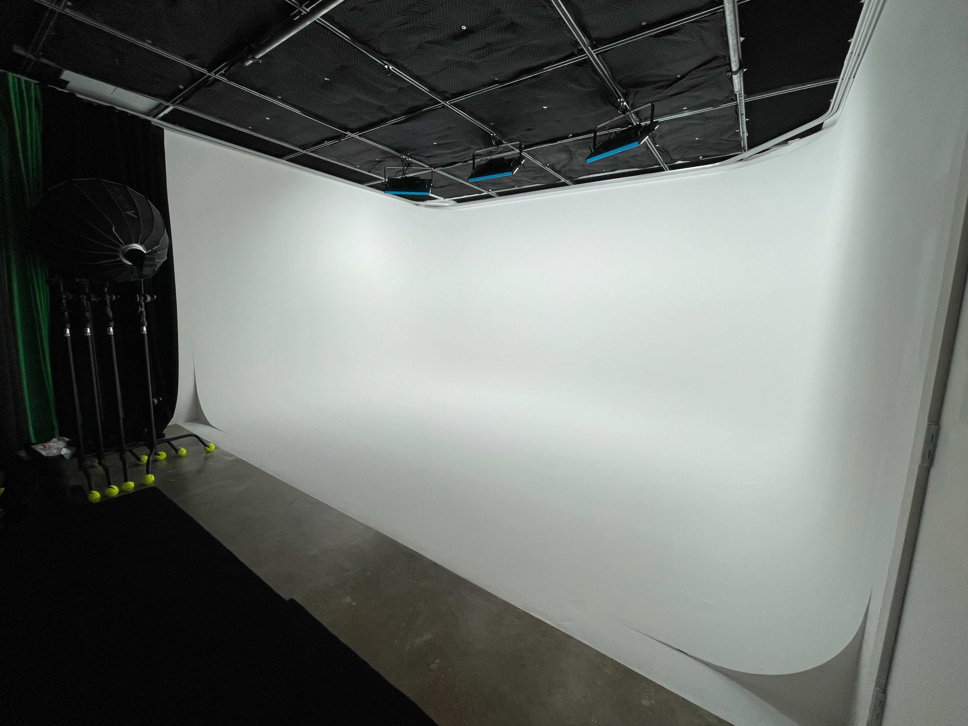 The image shows a photography studio with a seamless white backdrop and a setup for lighting.